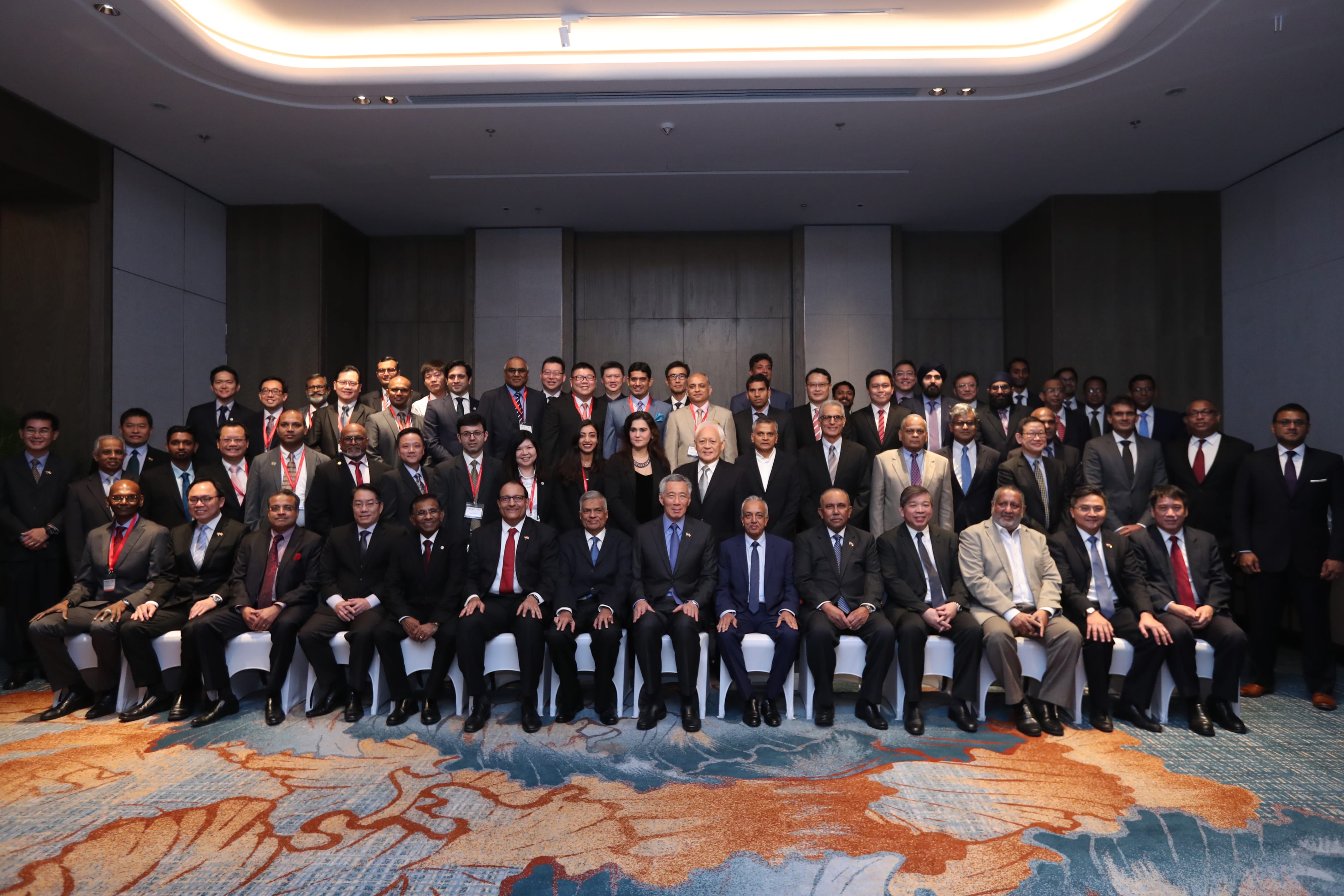 Large group of people in business attire posing for a photograph indoors.