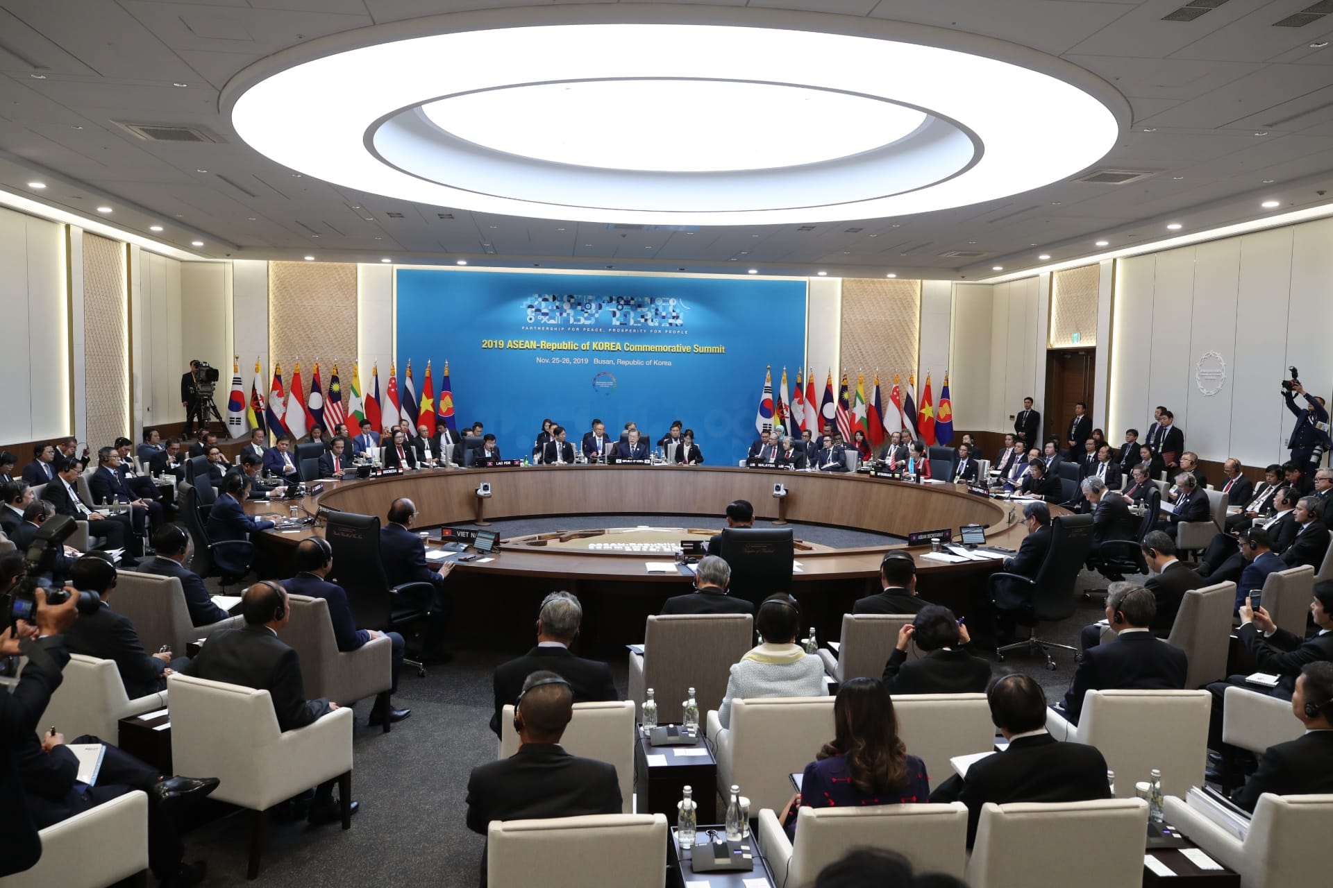 Large conference room with flag-lined dais and seated delegates.