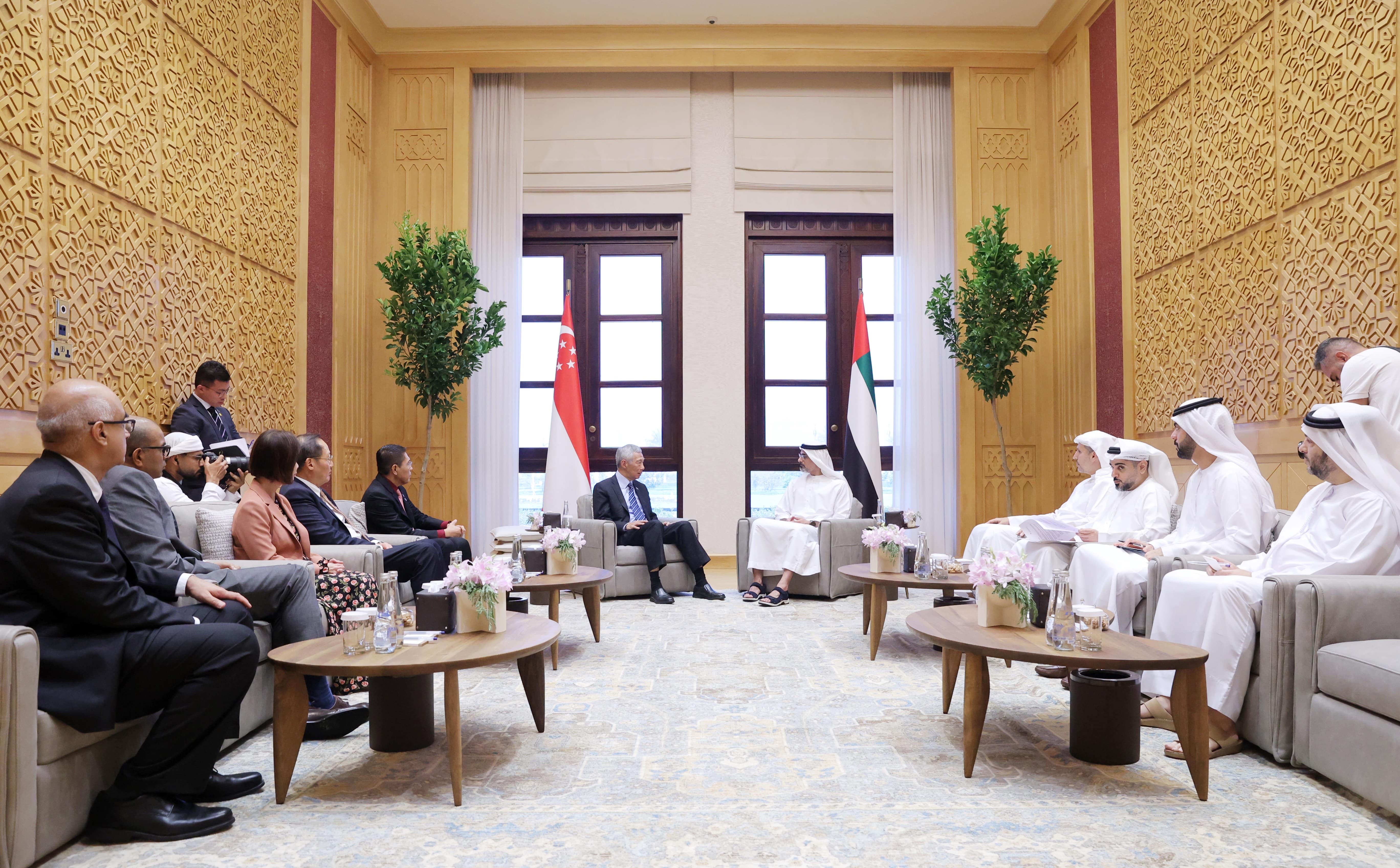 Group meeting: Singapore & UAE delegates in ornate room, flags behind seated leaders.