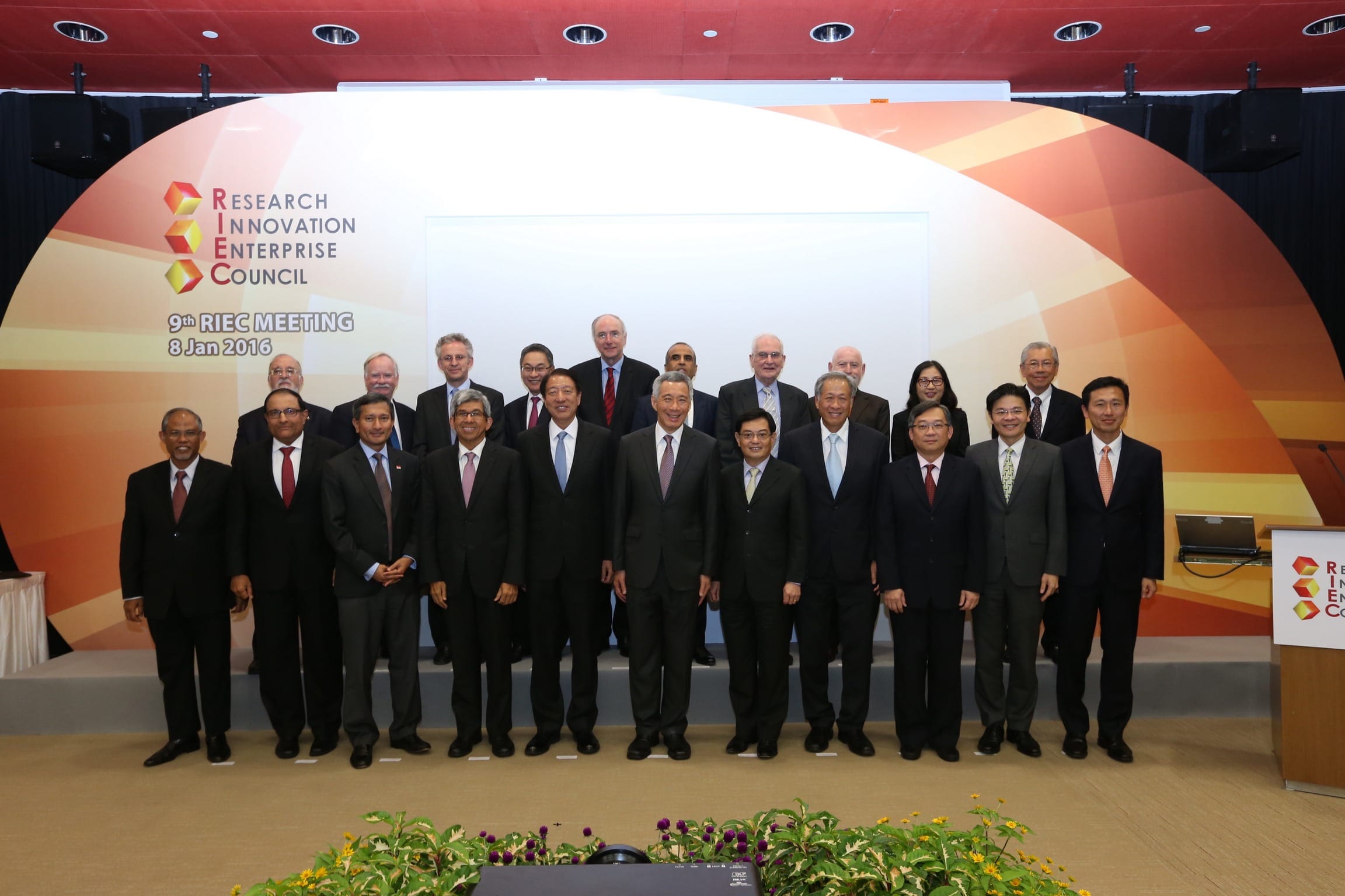 Group of people in suits posed in front of a "Research Innovation Enterprise Council" sign.