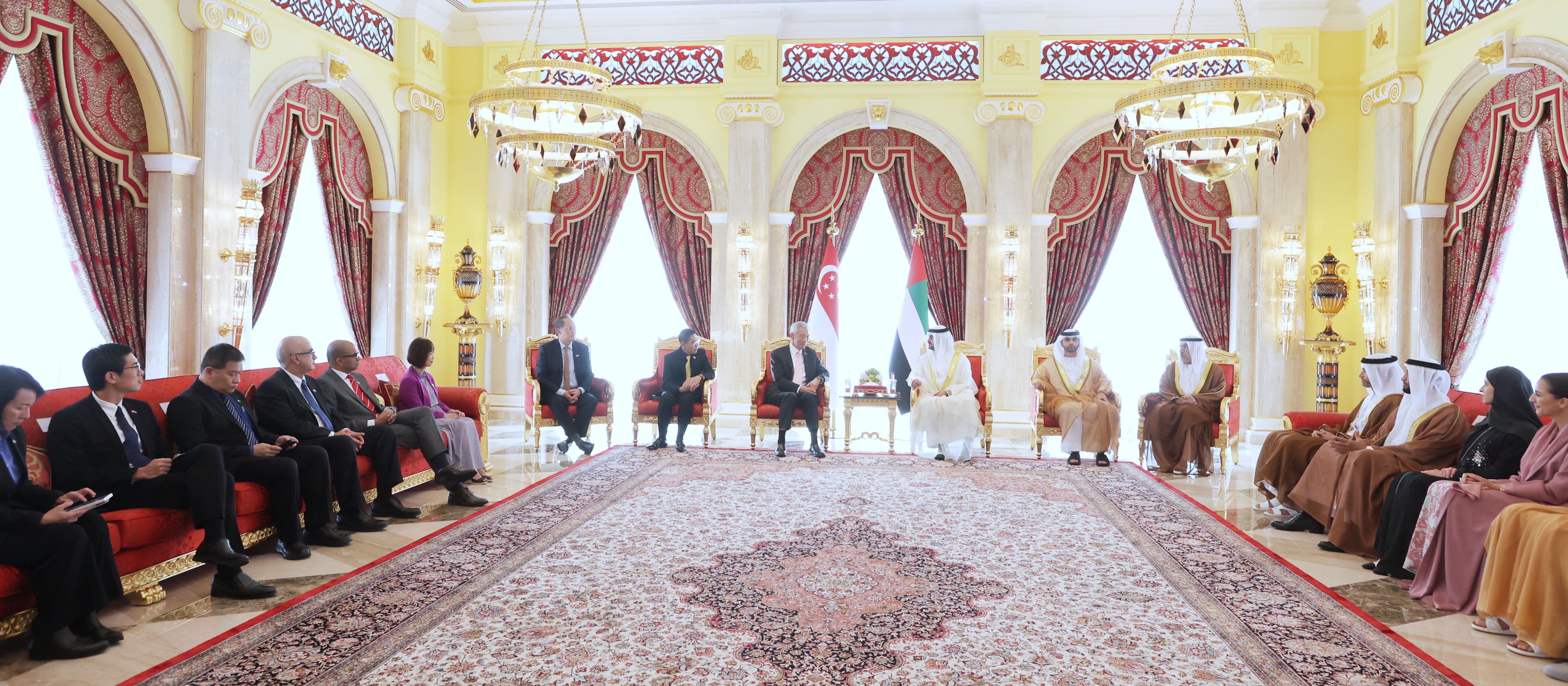 Meeting in ornate room. People seated, flags of Singapore and UAE visible.