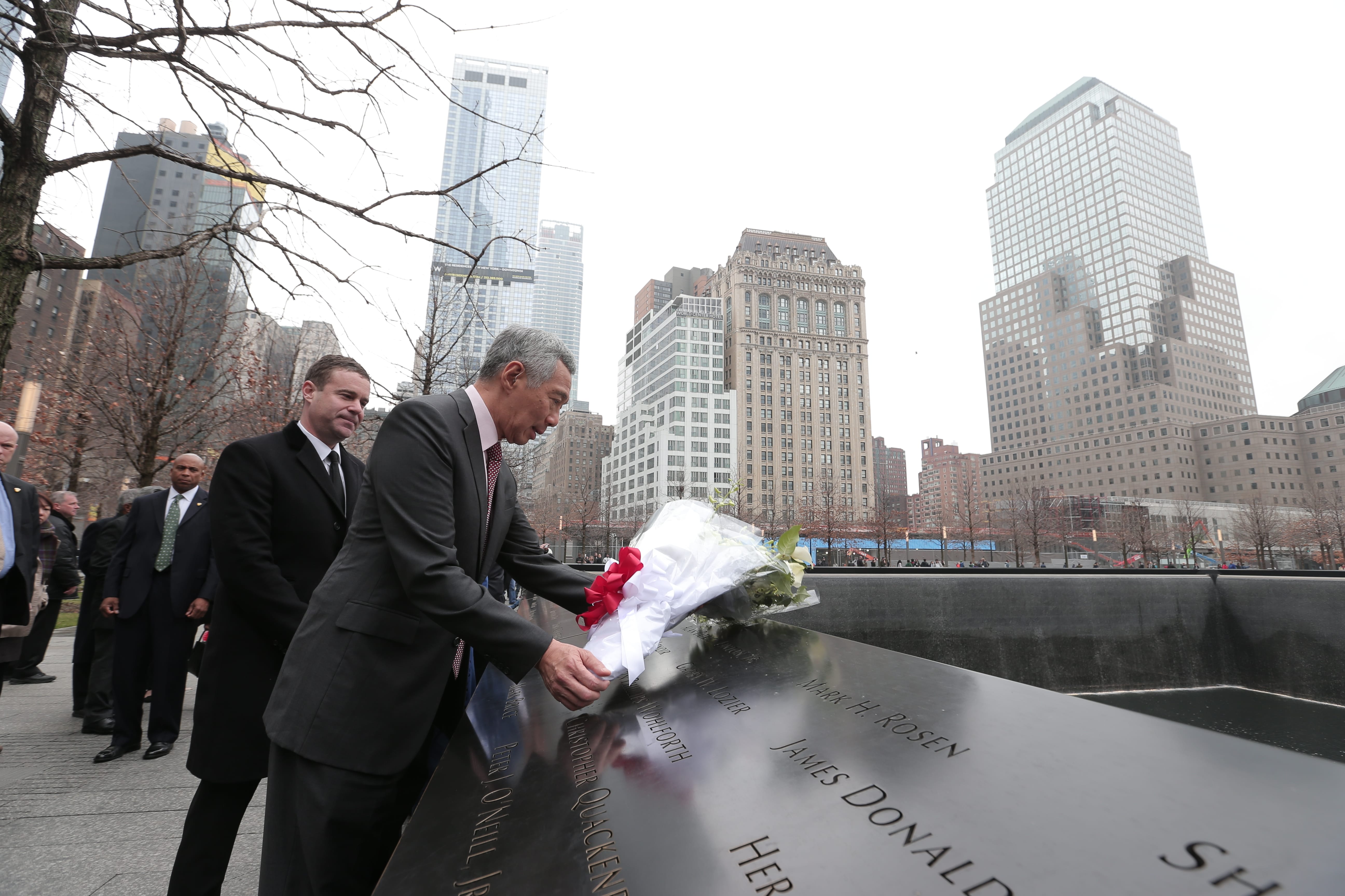 Lee Hsien Loong lays flowers at the 9/11 memorial, NYC skyscrapers in background.