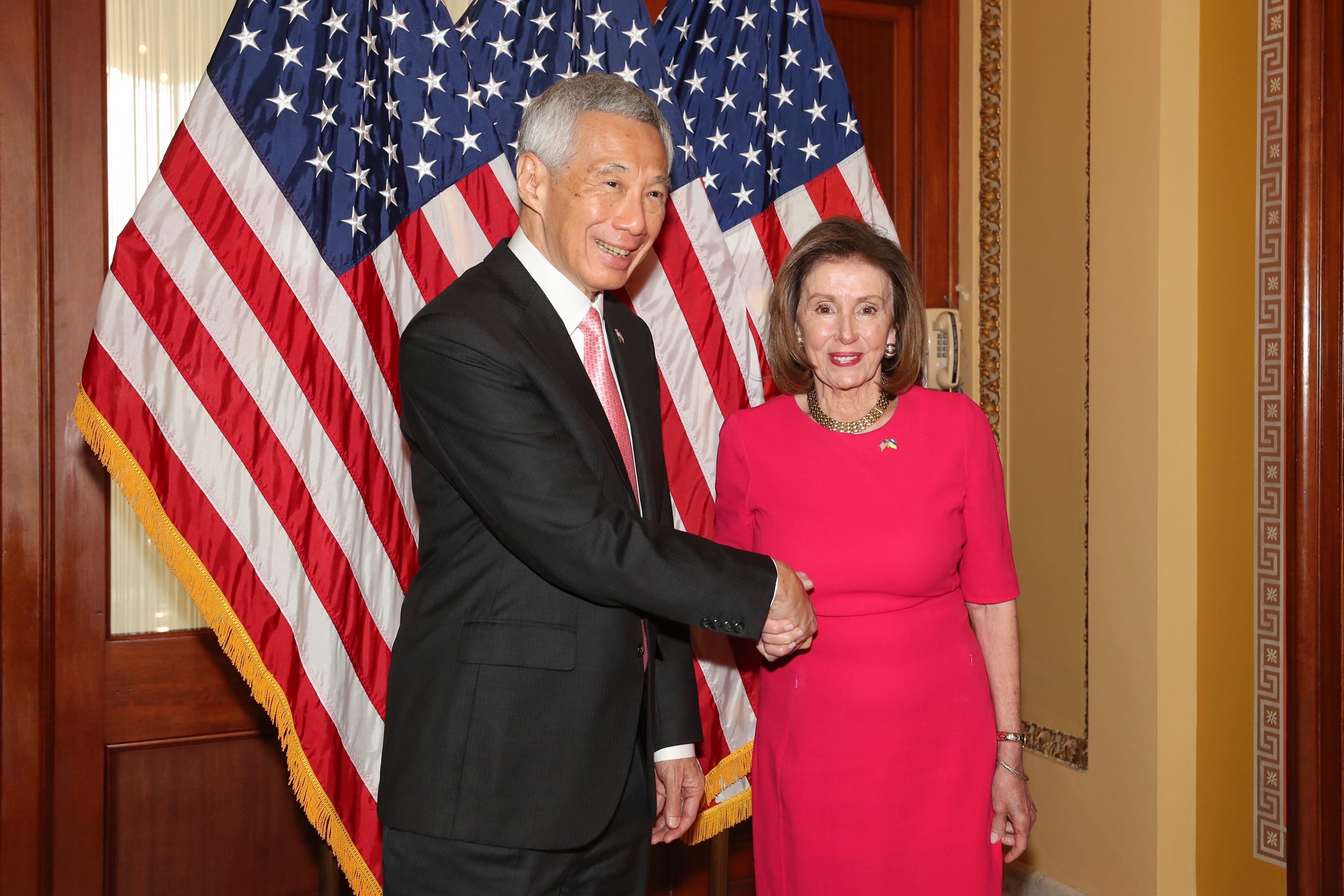 Lee Hsien Loong and Nancy Pelosi shaking hands with American flags in the background.