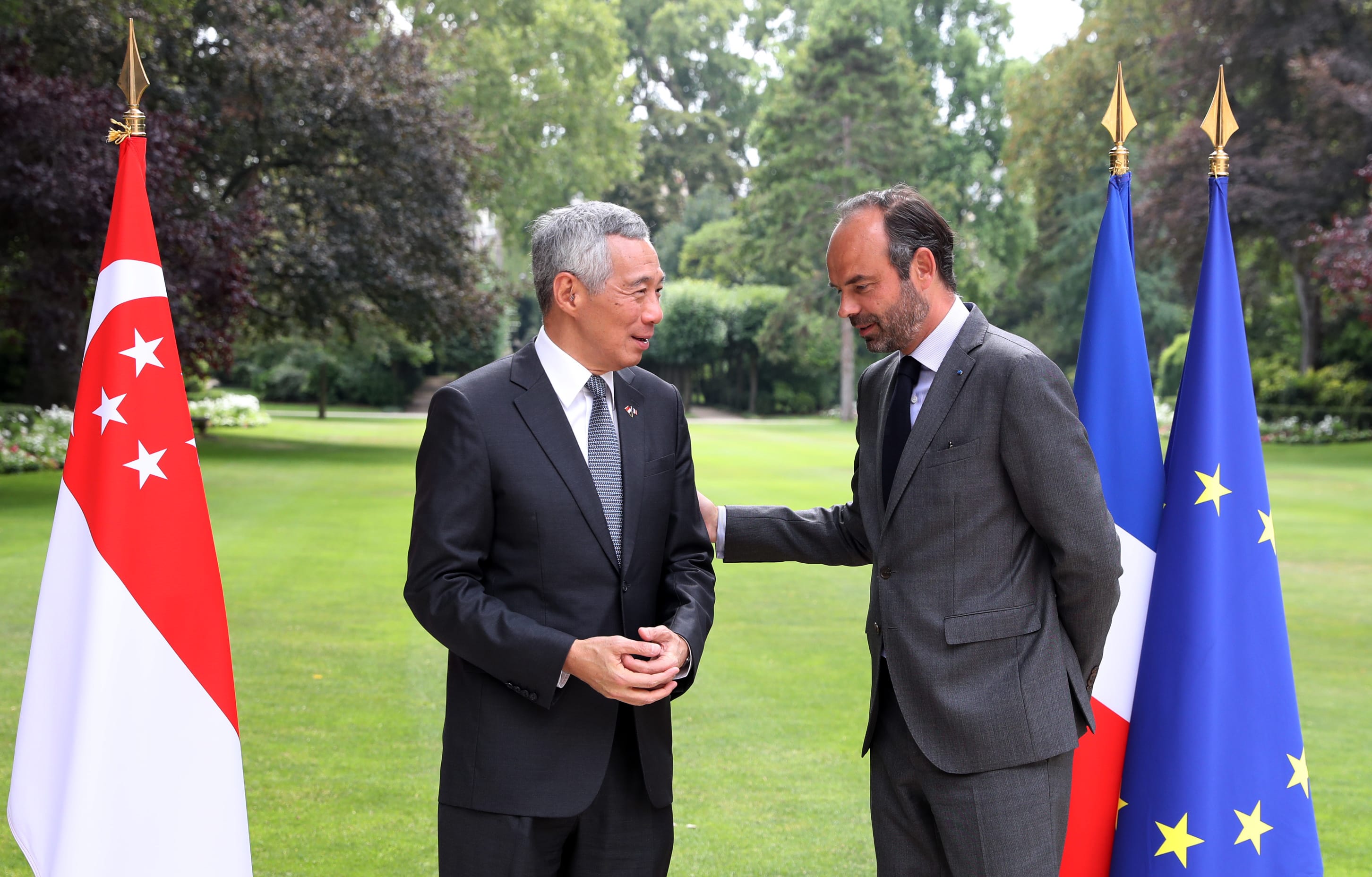 Singapore's Lee Hsien Loong and Édouard Philippe stand beside their nations' flags.