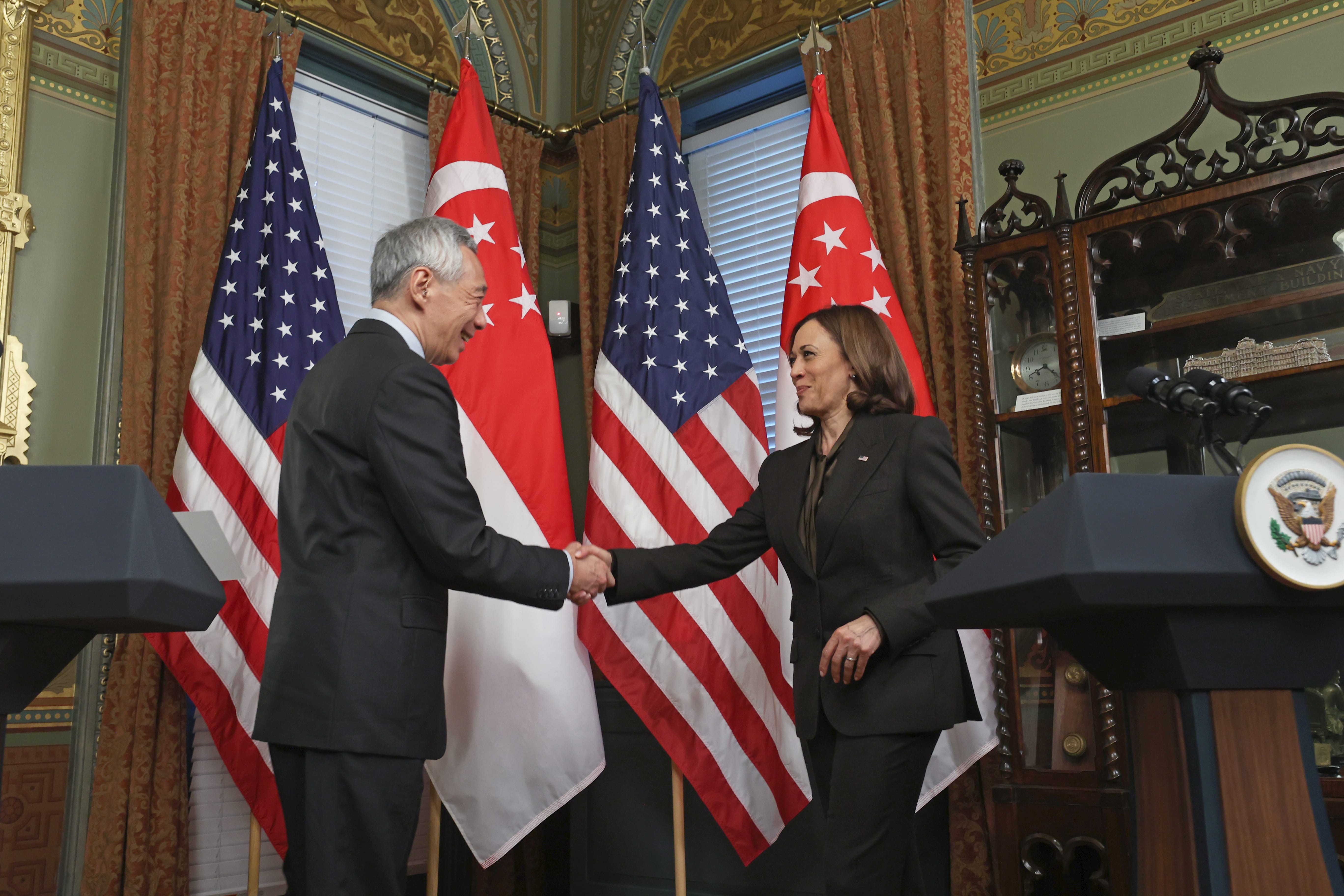 Kamala Harris & Lee Hsien Loong shaking hands before US and Singapore flags.
