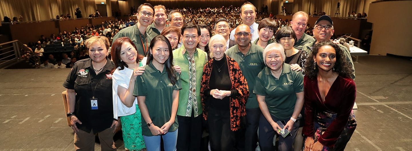 Jane Goodall with a diverse group onstage before an audience.