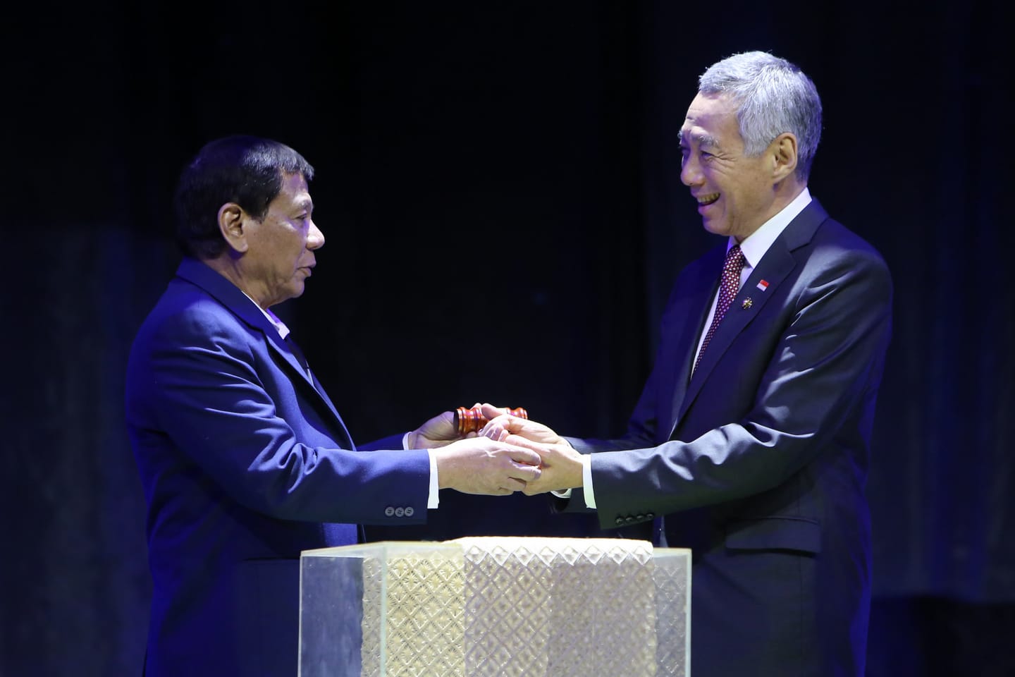 Rodrigo Duterte and Lee Hsien Loong exchange a gavel on a patterned podium.
