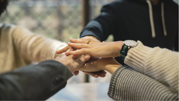 Close-up of hands stacked together, symbolising unity and teamwork among colleagues.