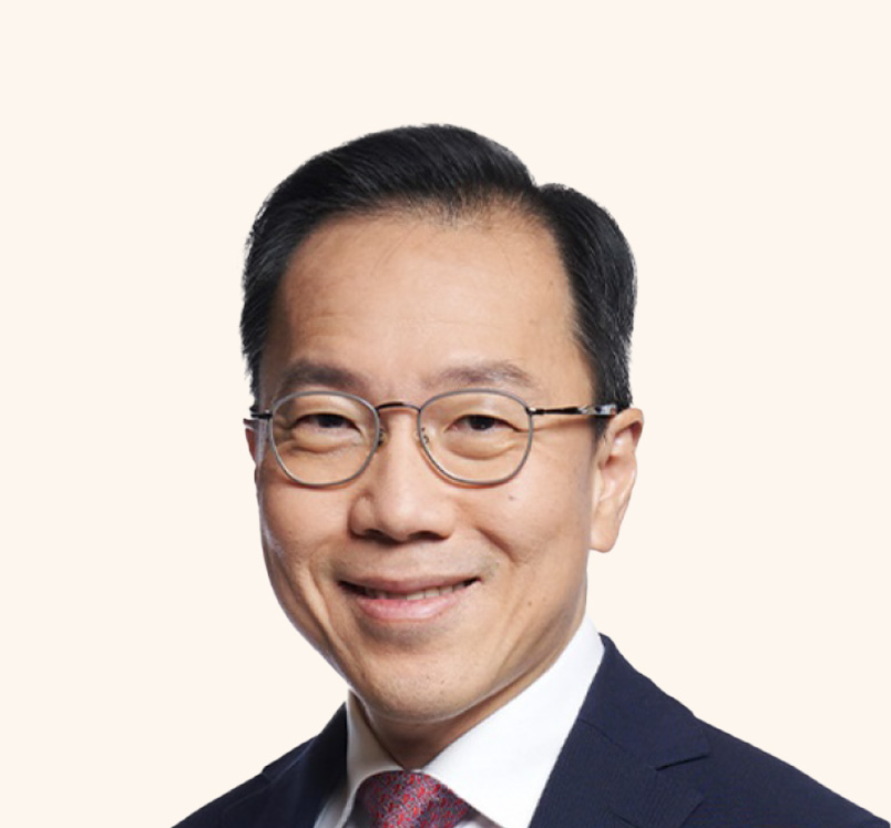 Permanent Secretary Dr Beh Swan Gin in suit and glasses, smiling against pale background.