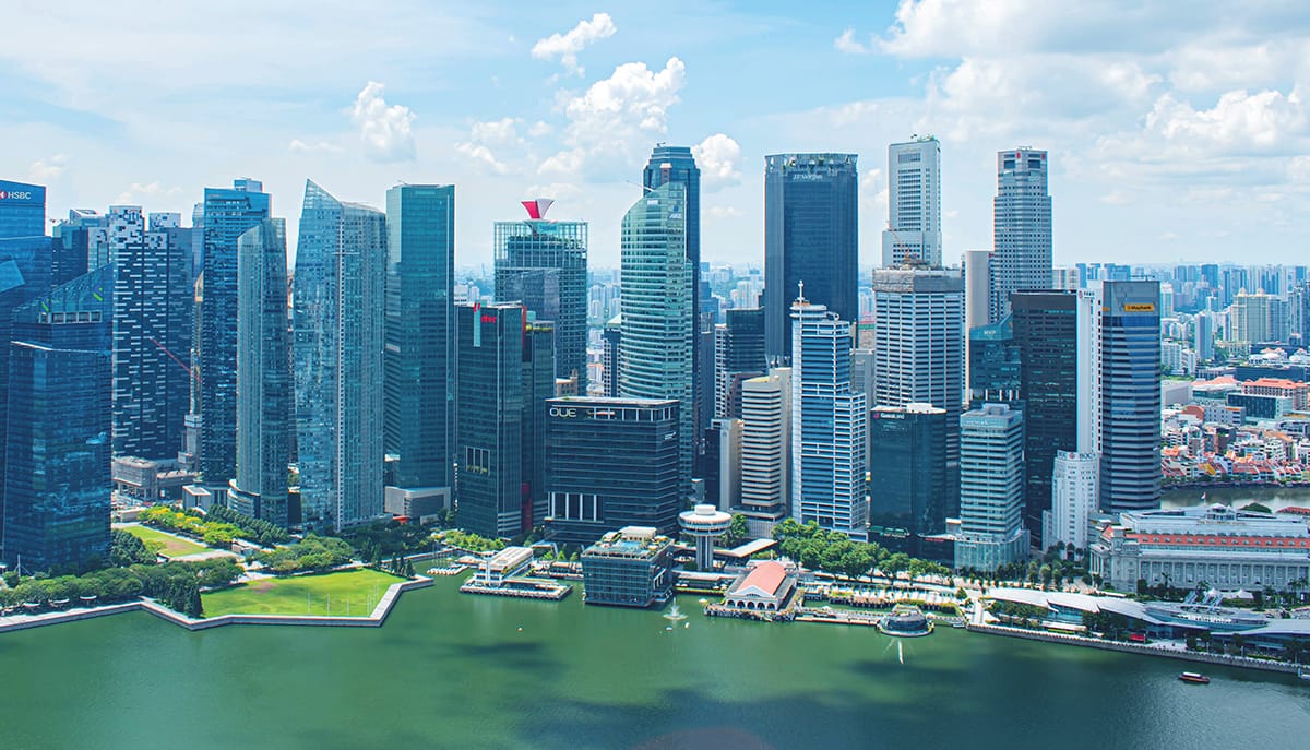 Panoramic view of Singapore’s waterfront skyscrapers under blue sky.
