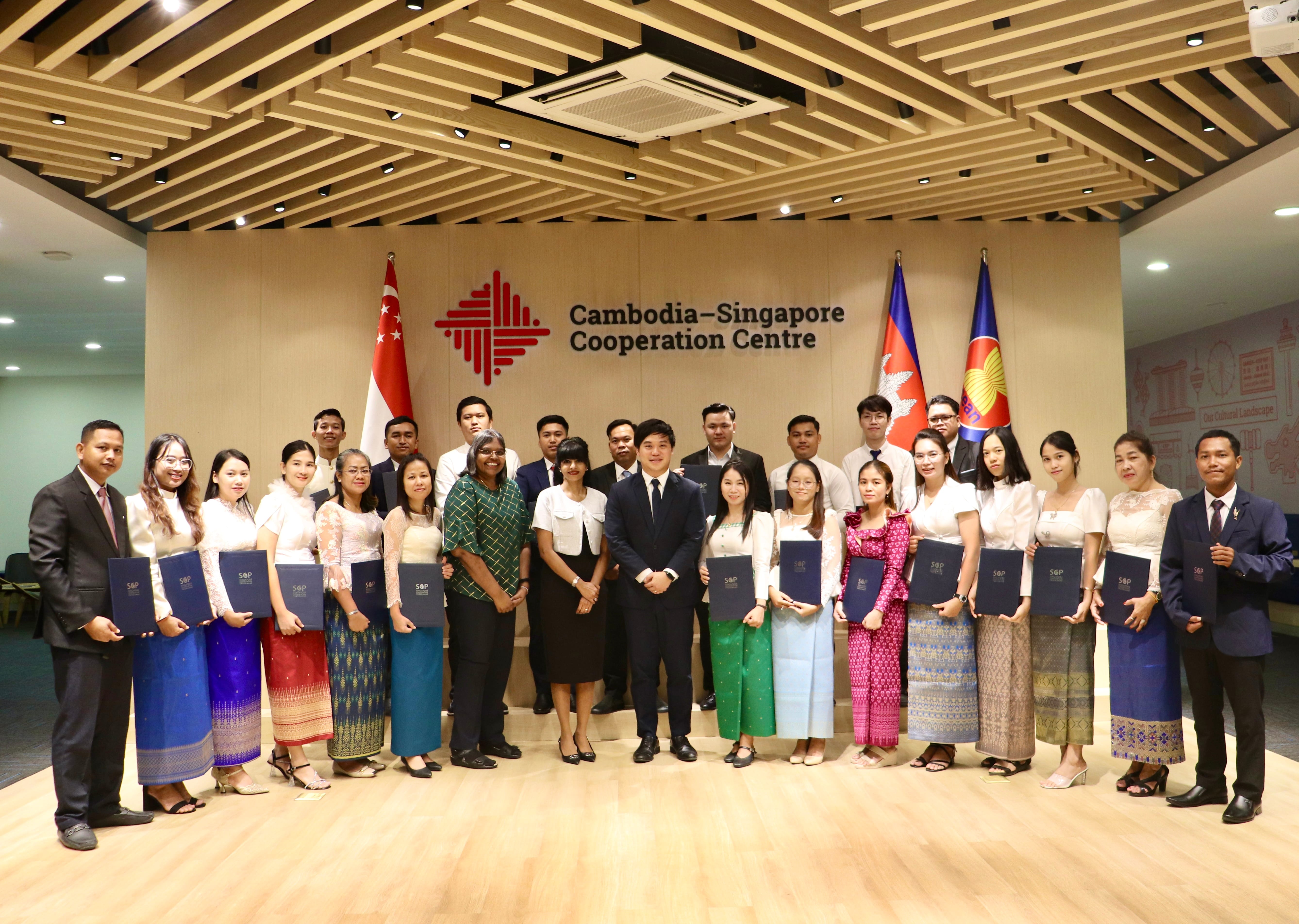 Group of people stand holding S&P folders in front of Cambodia-Singapore Cooperation Centre sign.