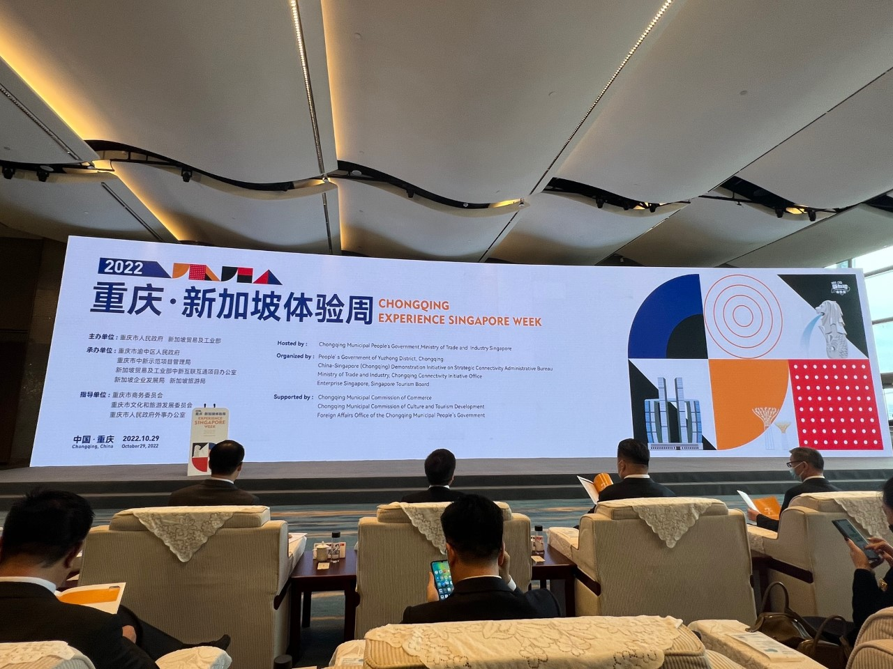 Audience facing a large screen for "Chongqing Experience Singapore Week" conference.