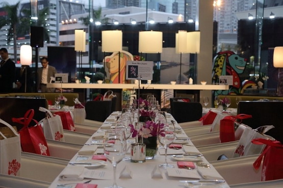 Formal dining table set with flowers, gifts, glasses, and Britto art in background.