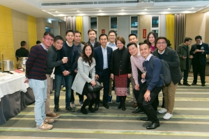 Group of people pose indoors with a man in suit at center. Buffet table visible to the left.