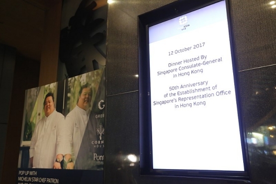 Poster with chefs and a digital sign announcing a Singapore Consulate dinner in Hong Kong.