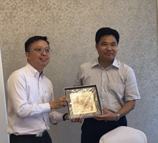 Two men in shirts holding a framed picture, one presenting it to the other.