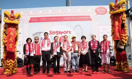 People on stage flanked by lion dancers at a Singapore Fiesta event.