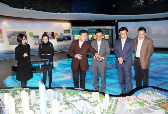 Group of people examining a cityscape model in a modern showroom.