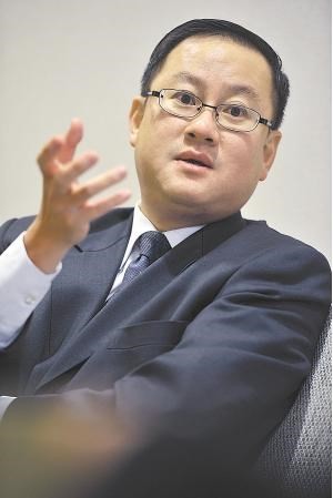 Man in suit and glasses gesturing with hand.