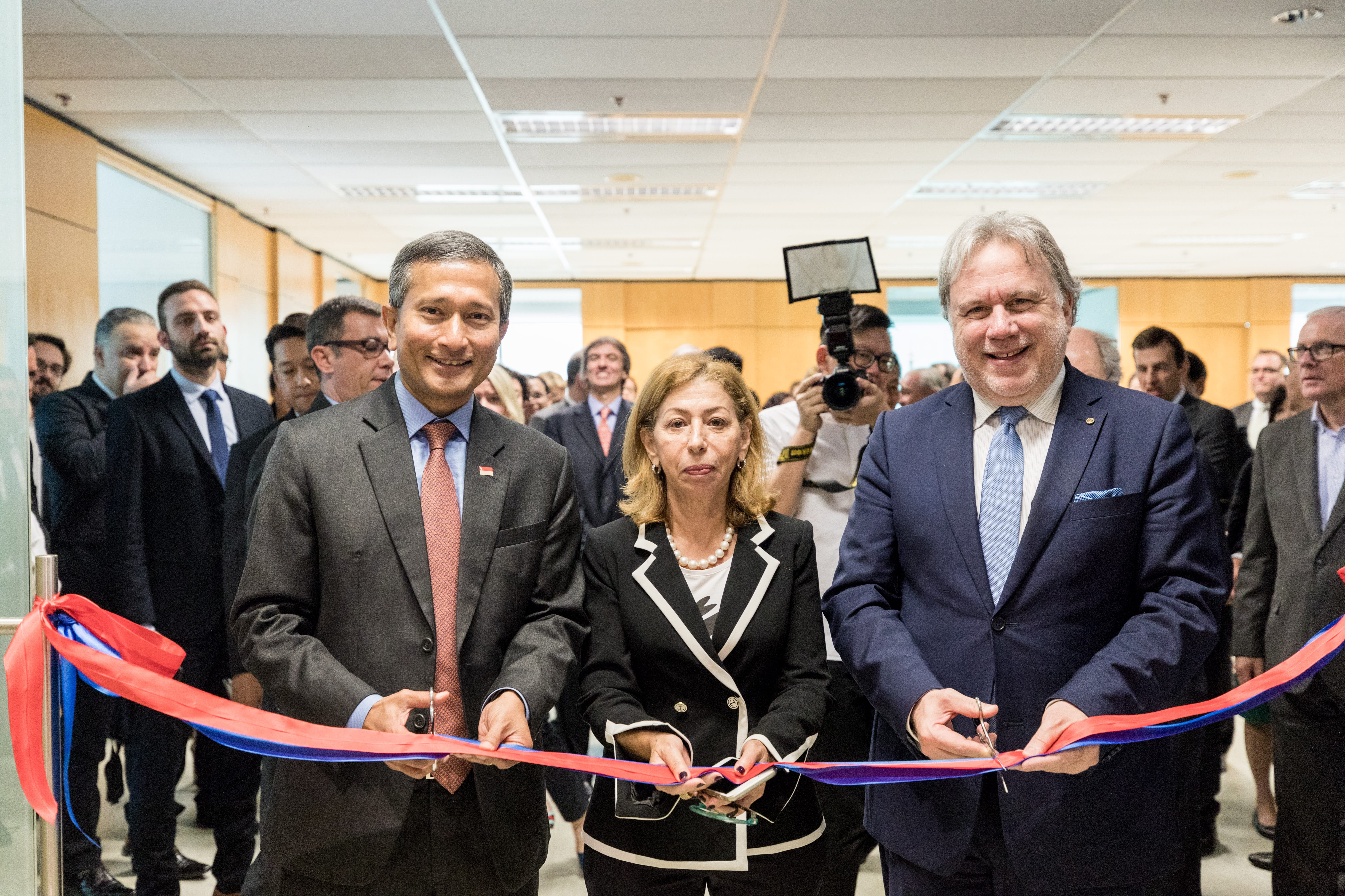 Two men in suits shaking hands in front of a G20 Development Ministers' Meeting backdrop.