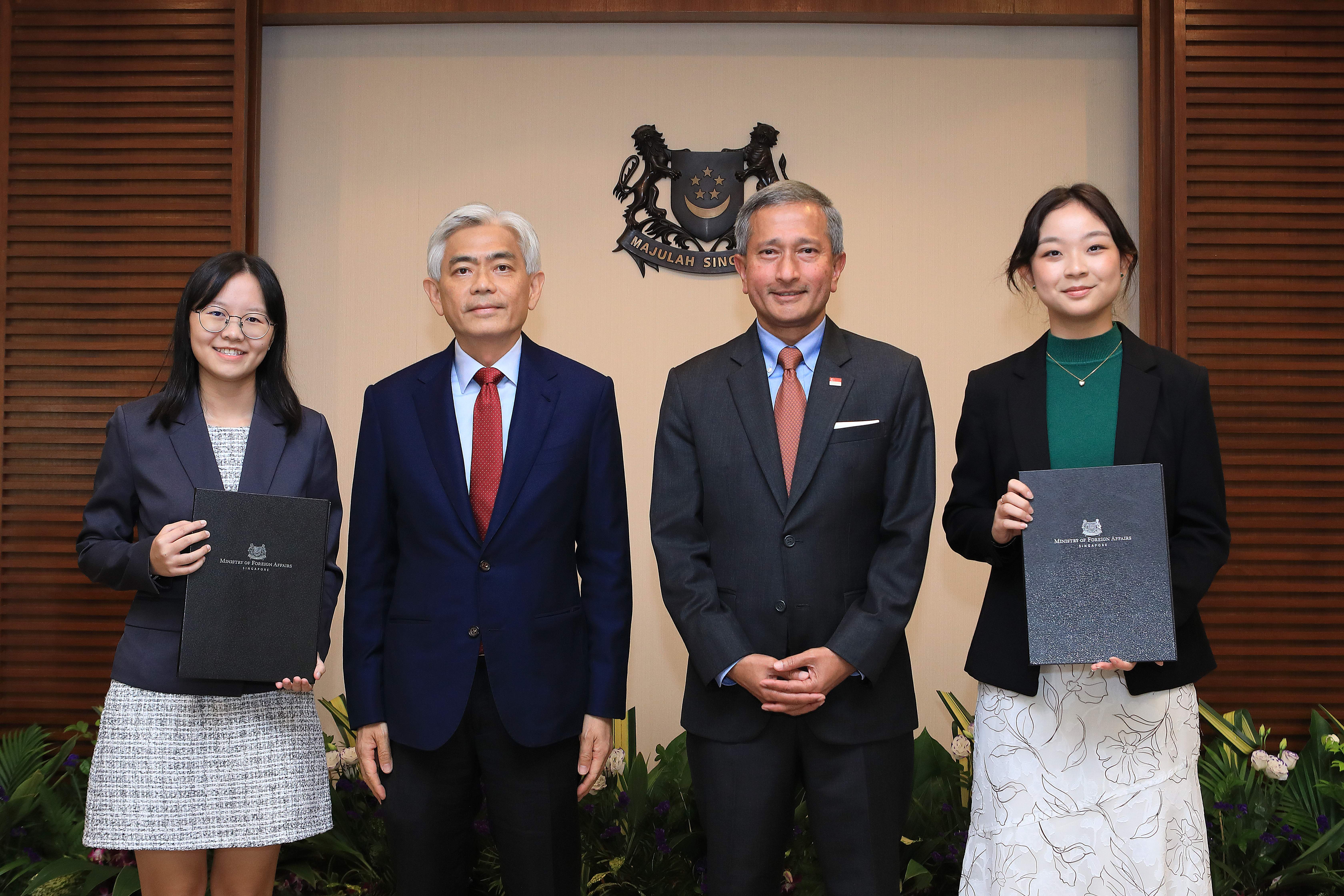 Four people pose formally holding Ministry of Foreign Affairs Singapore documents.