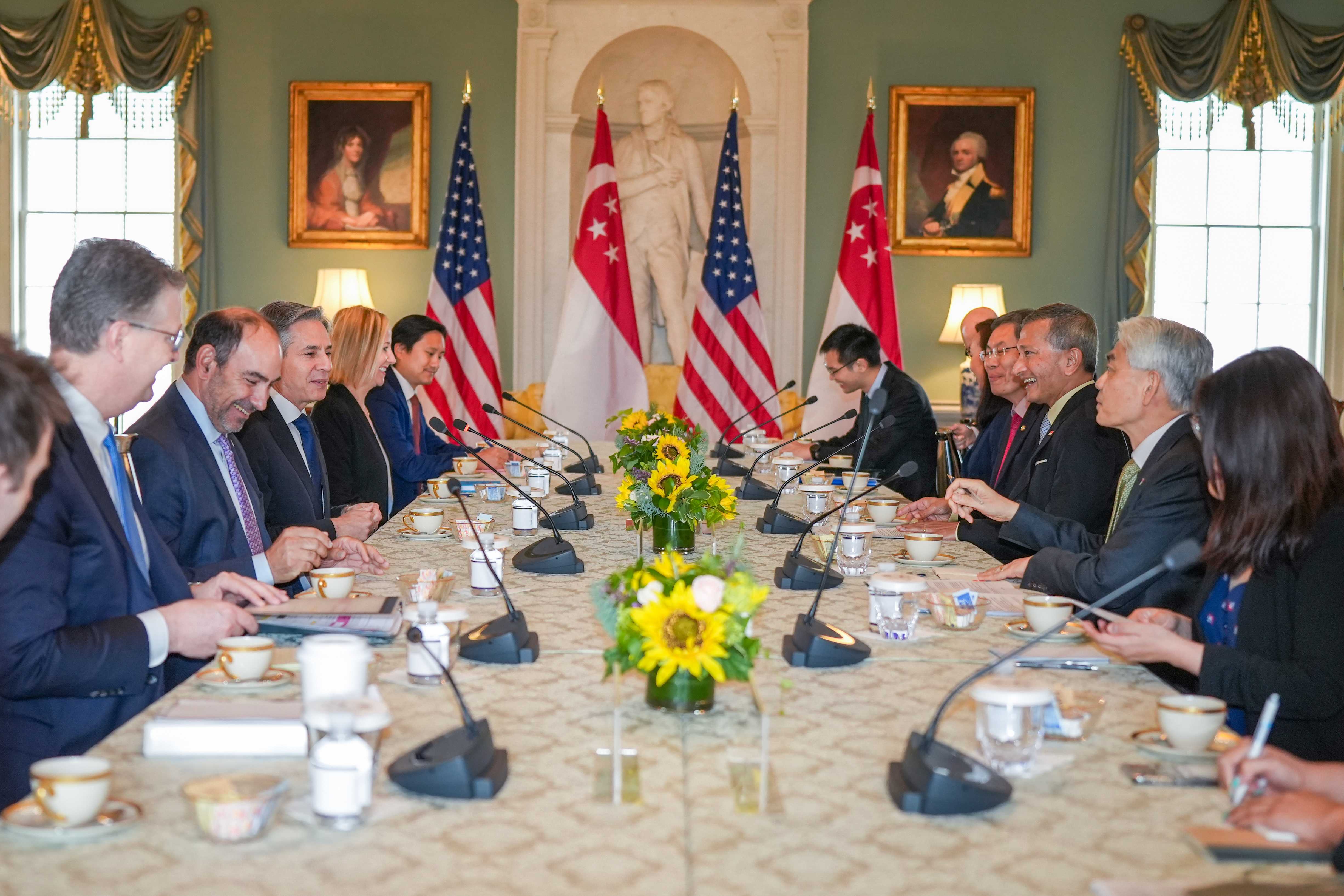 People at a long table with US and Singapore flags, and sunflower centerpieces.