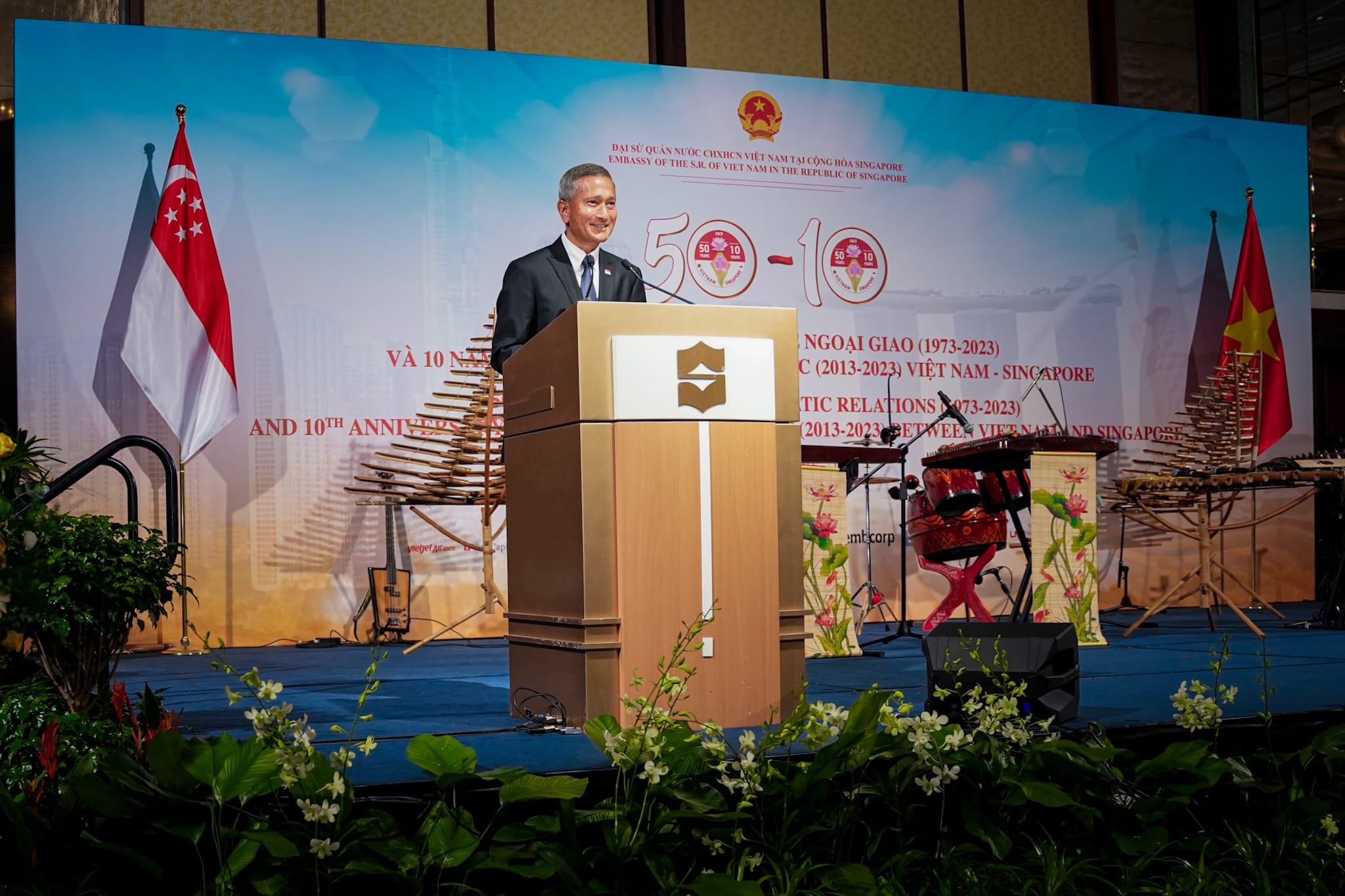 Man at podium before backdrop with Singapore and Vietnam flags celebrating diplomatic ties.