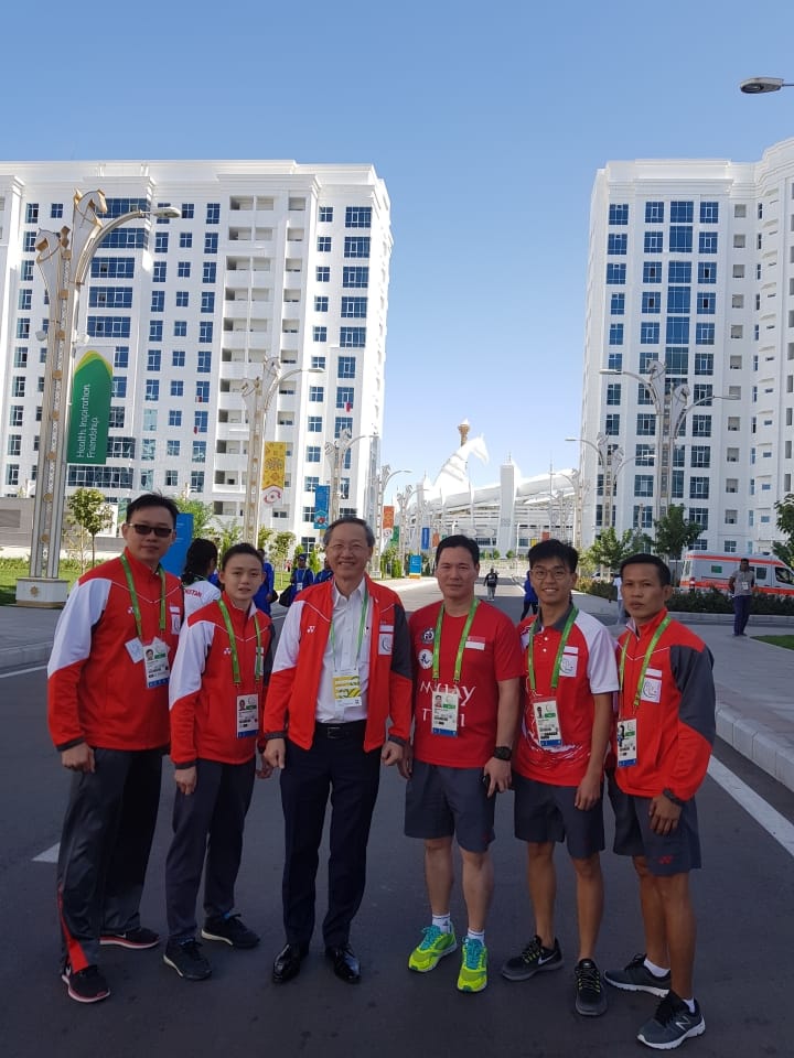 Group of people in red and white jackets posing on a street with white buildings.
