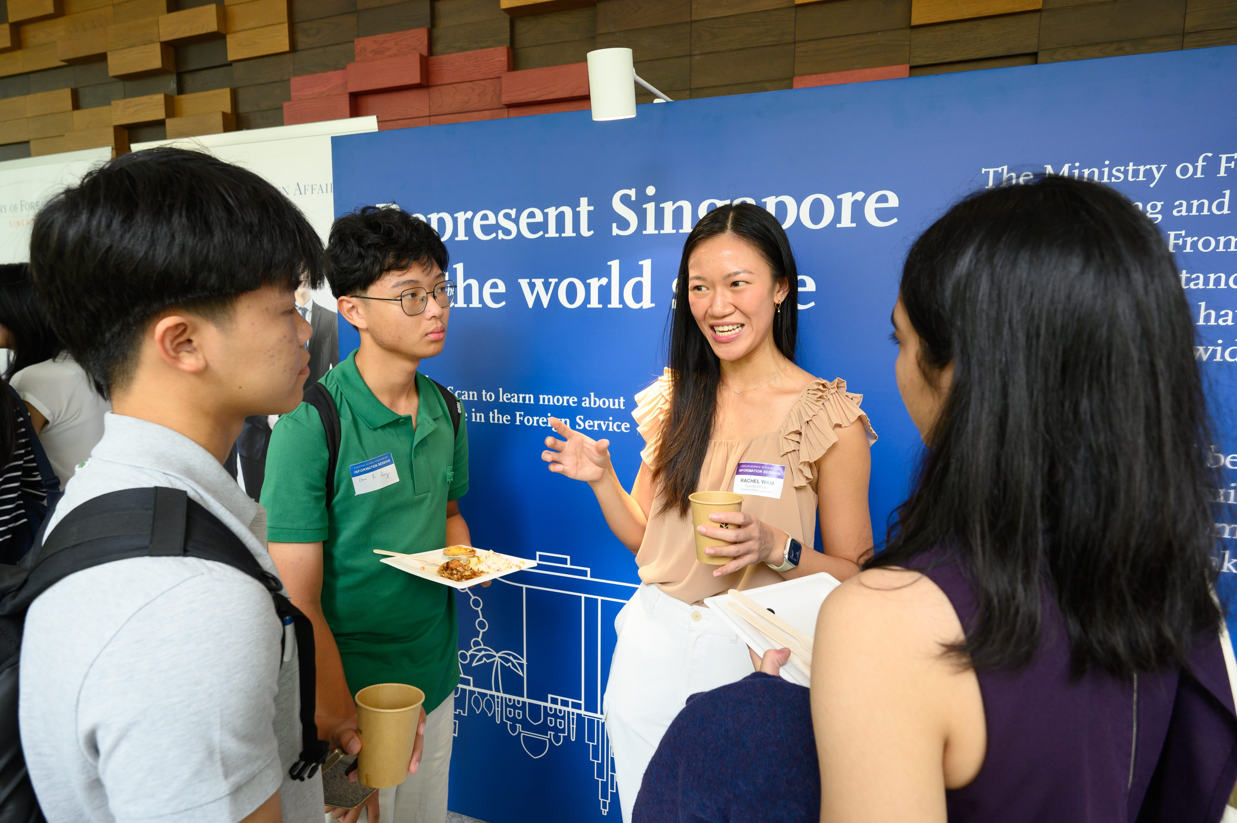 Attendee speaking with students at an MFA booth on representing Singapore