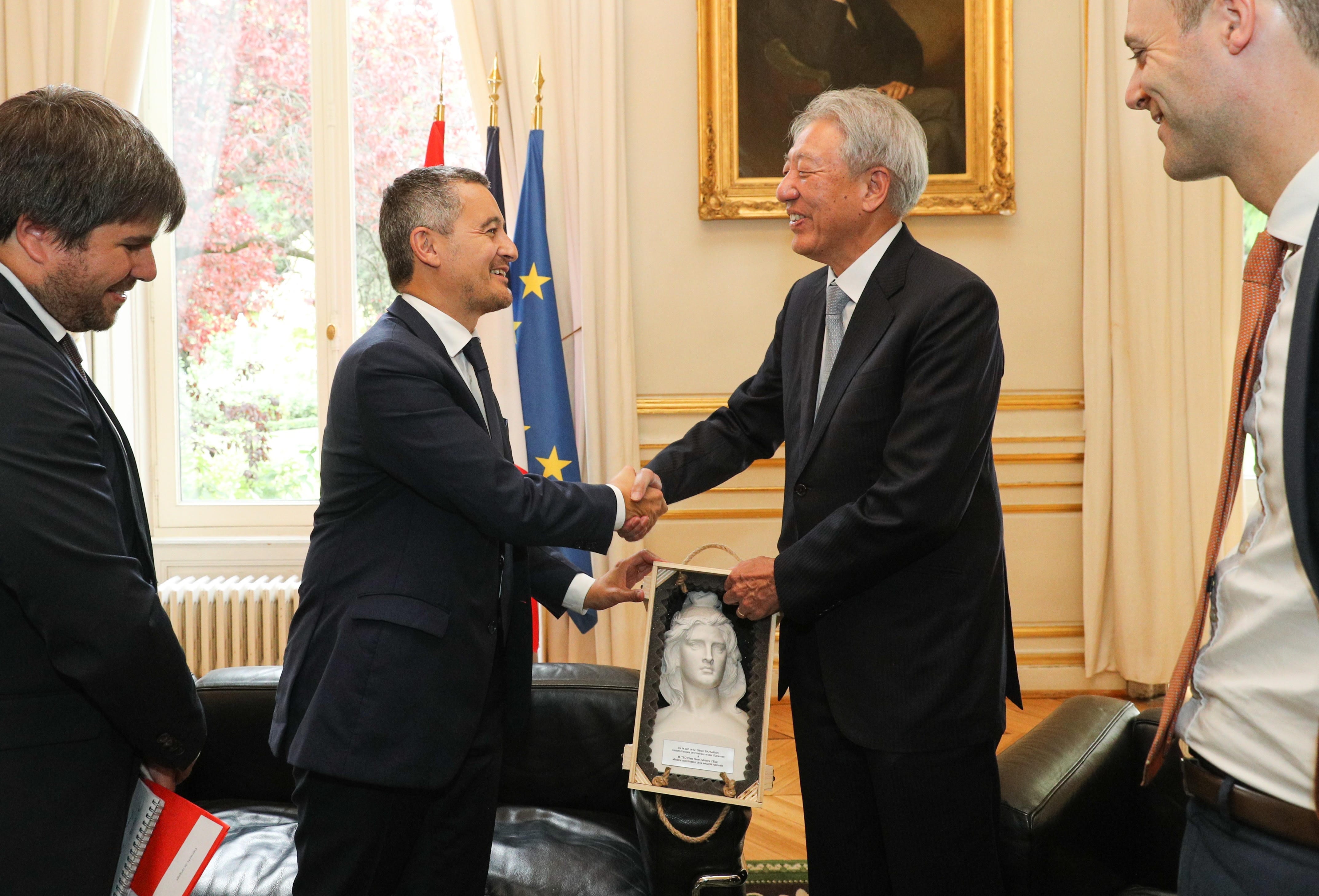 Group of people posed on a red carpeted staircase with white railing, with floral arrangements.