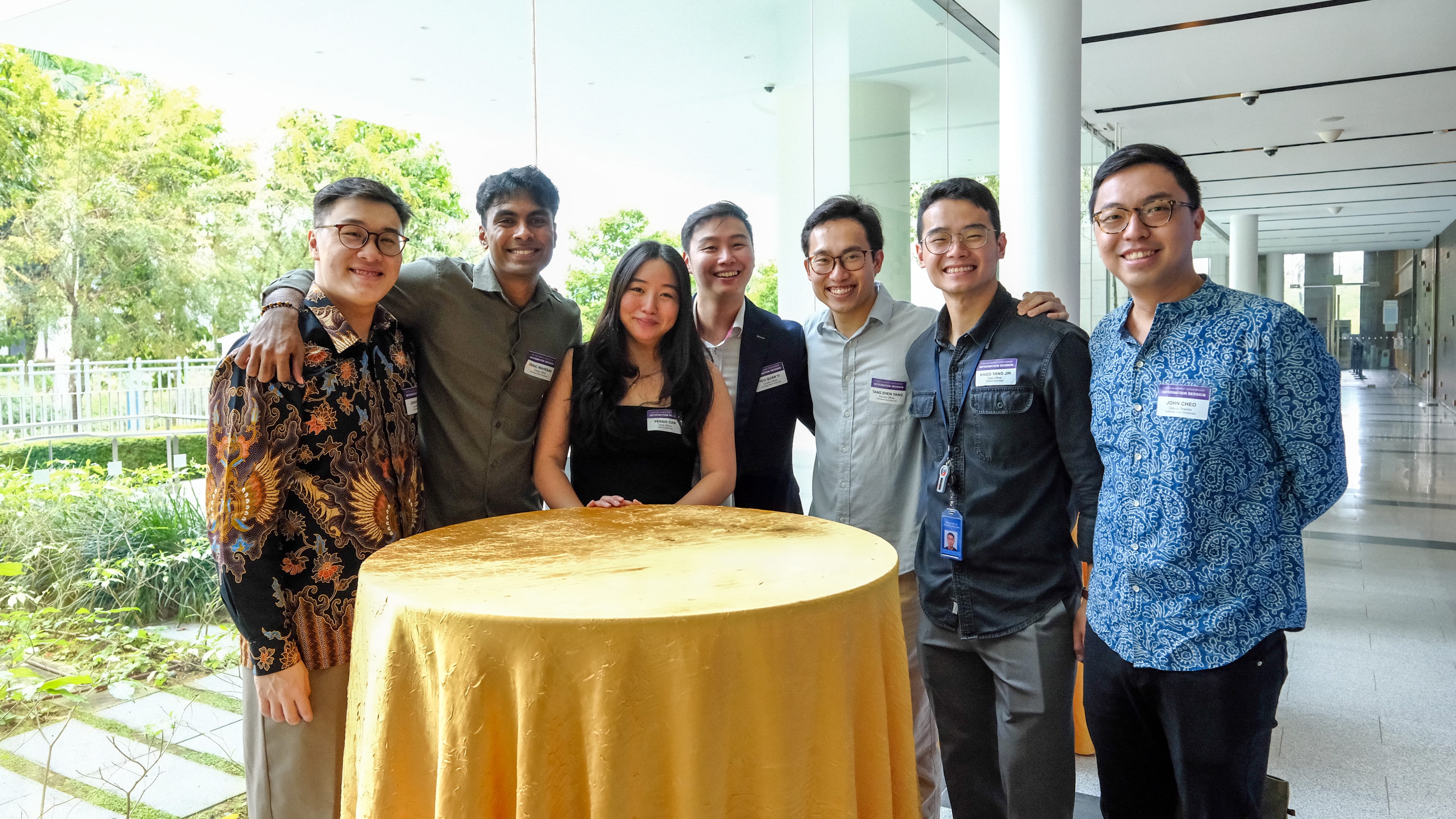 Group of young professionals posing around a round table with gold cloth