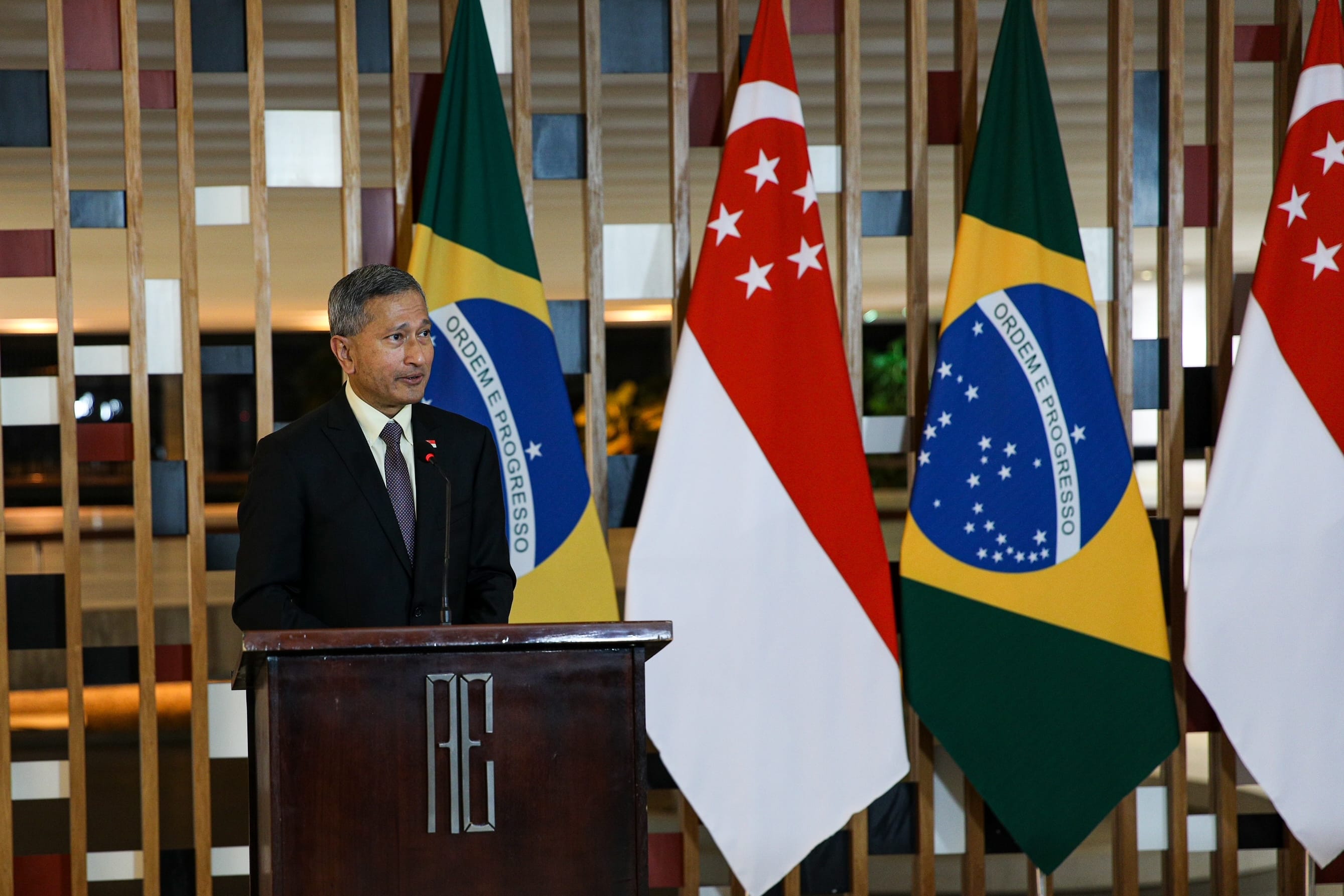 Man at podium with Brazilian & Singaporean flags.