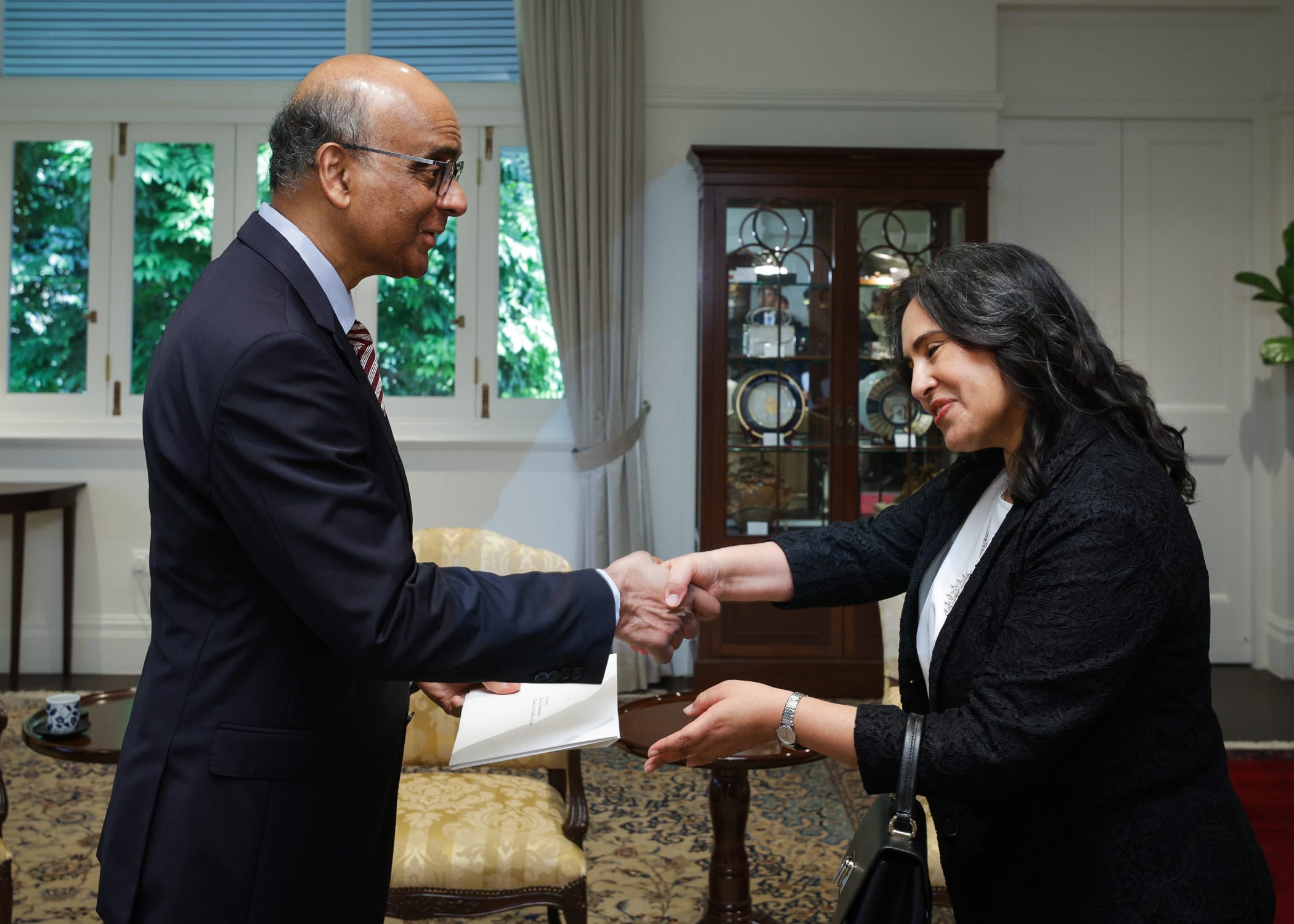 President Halimah Yacob shaking hands with a man holding a document.