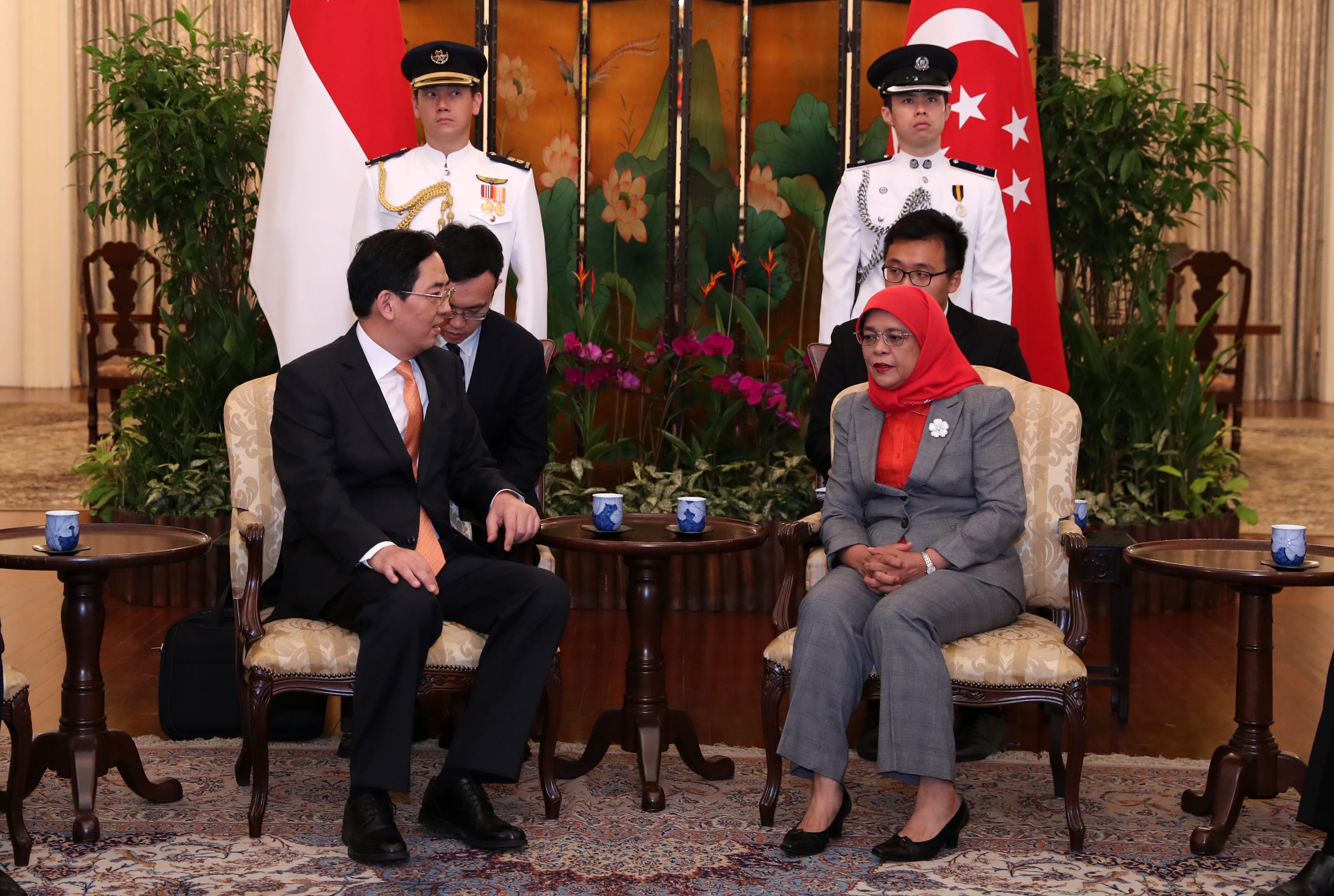 President Halimah Yacob and guest seated with guards and Singapore flag in background.