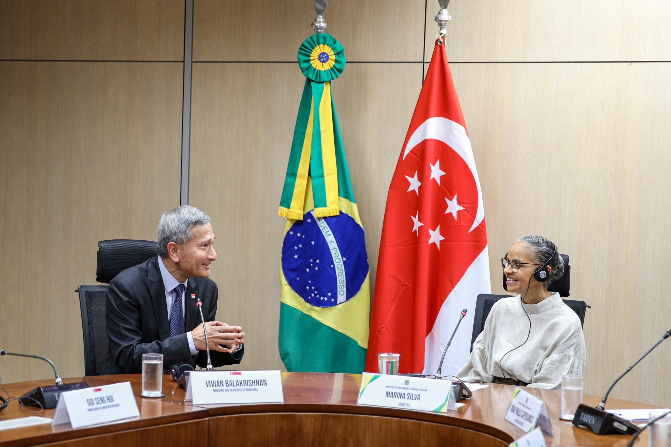 Vivian Balakrishnan & Marina Silva at table with Brazilian & Singapore flags behind them.