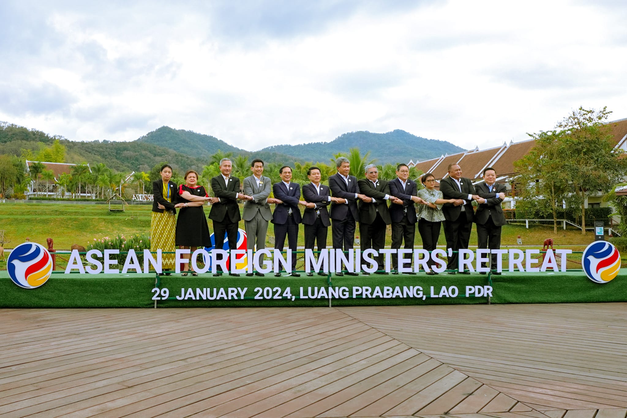 Group of ministers holding arms together above "ASEAN FOREIGN MINISTERS' RETREAT" sign.