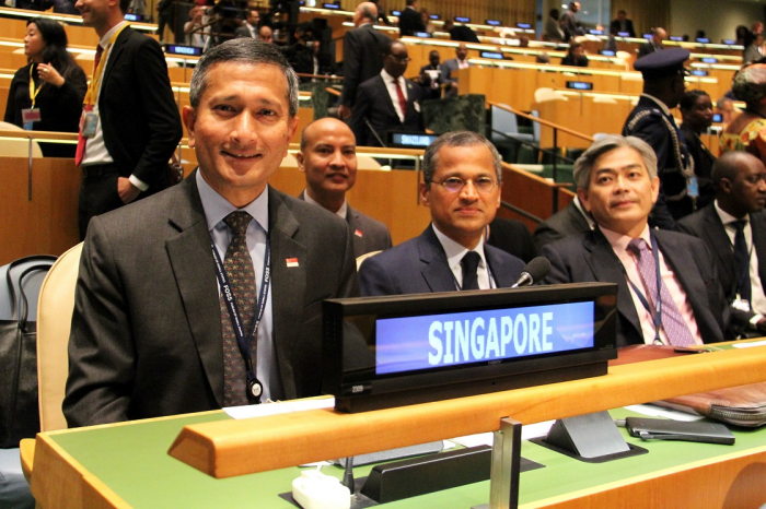 Singapore delegation at a conference; "SINGAPORE" displayed on a blue sign.