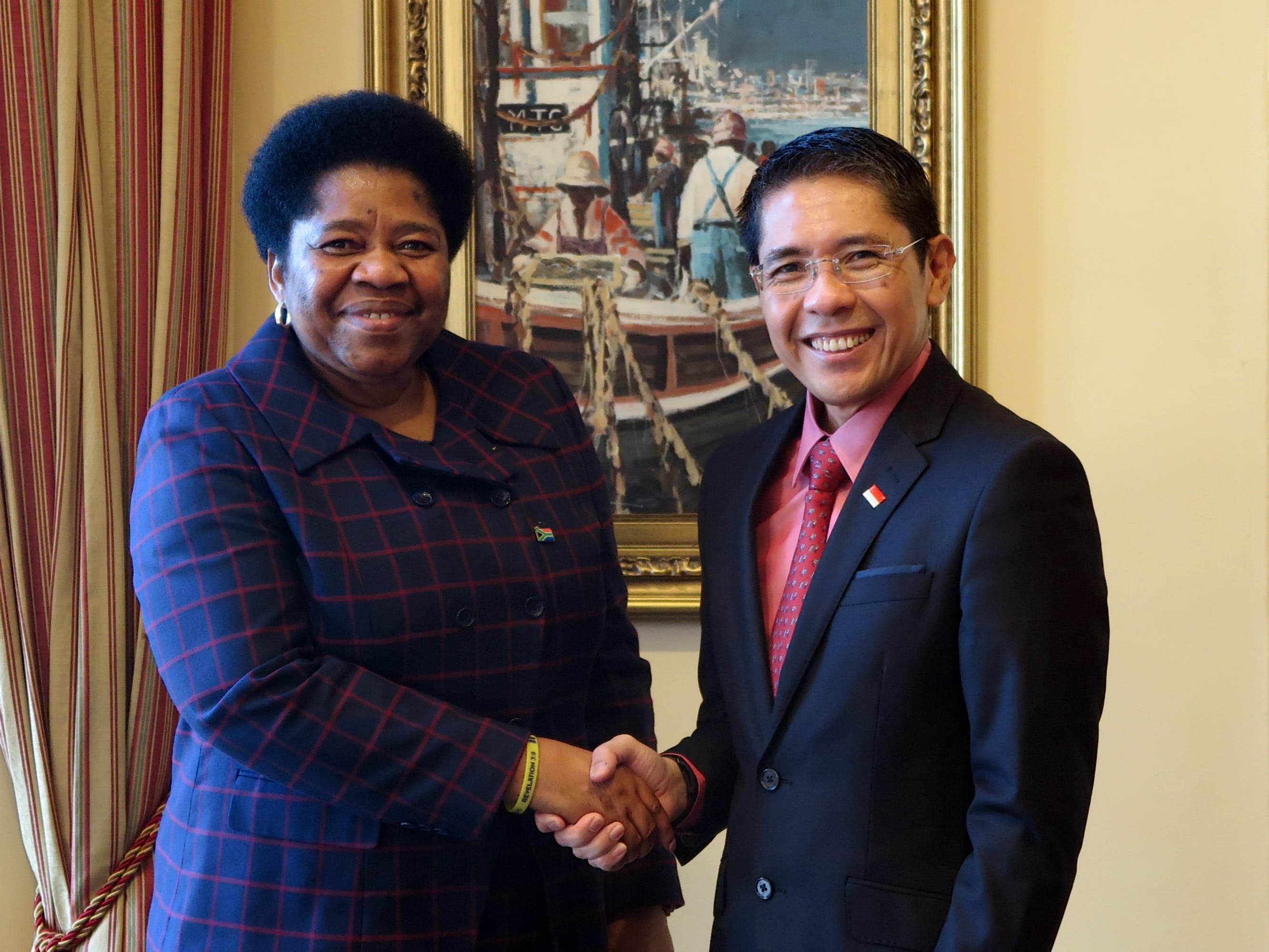 Two men in suits shaking hands in front of a G20 Development Ministers' Meeting backdrop.