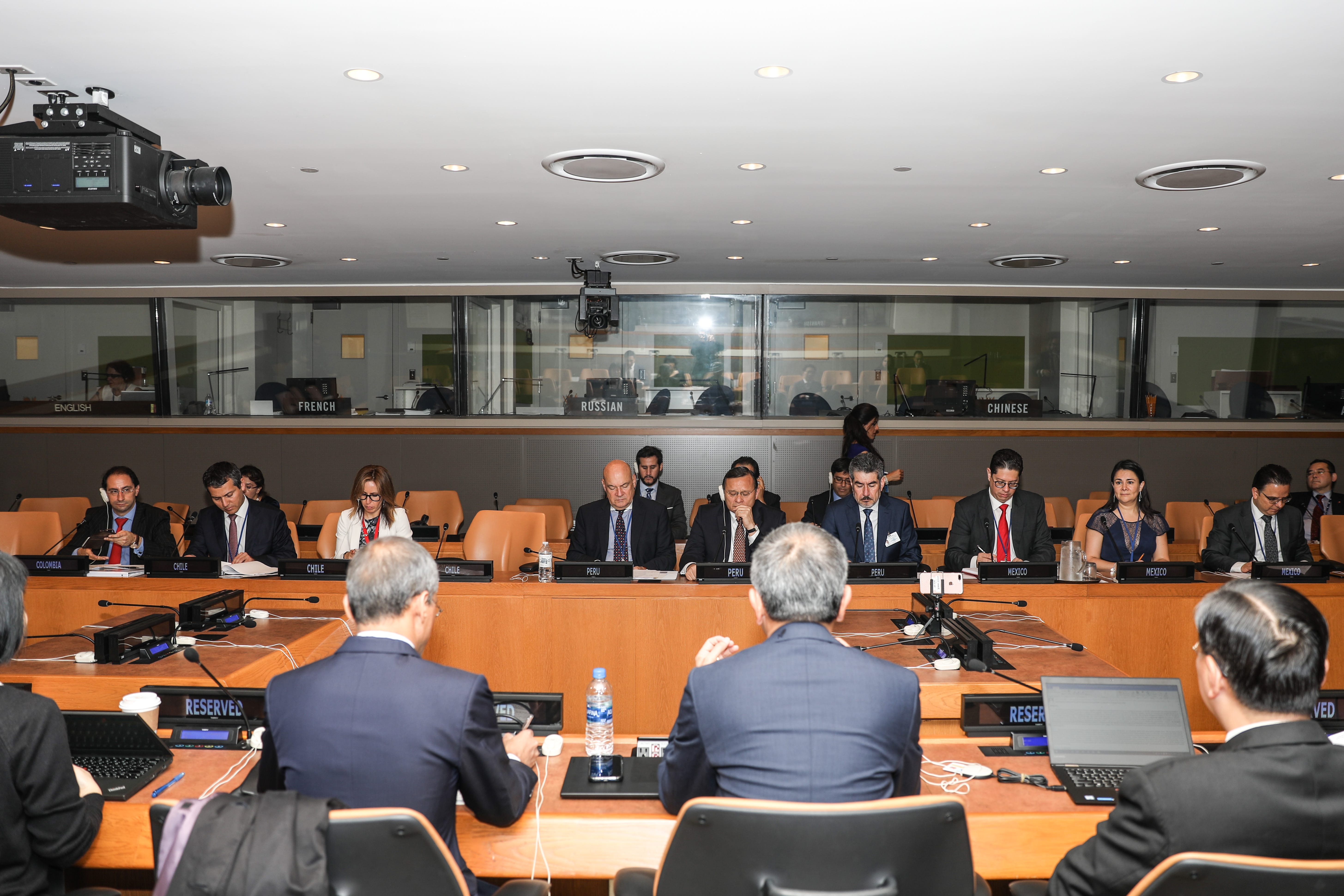 People at international conference; nameplates read countries like Colombia, Chile, Peru, Mexico, and languages.