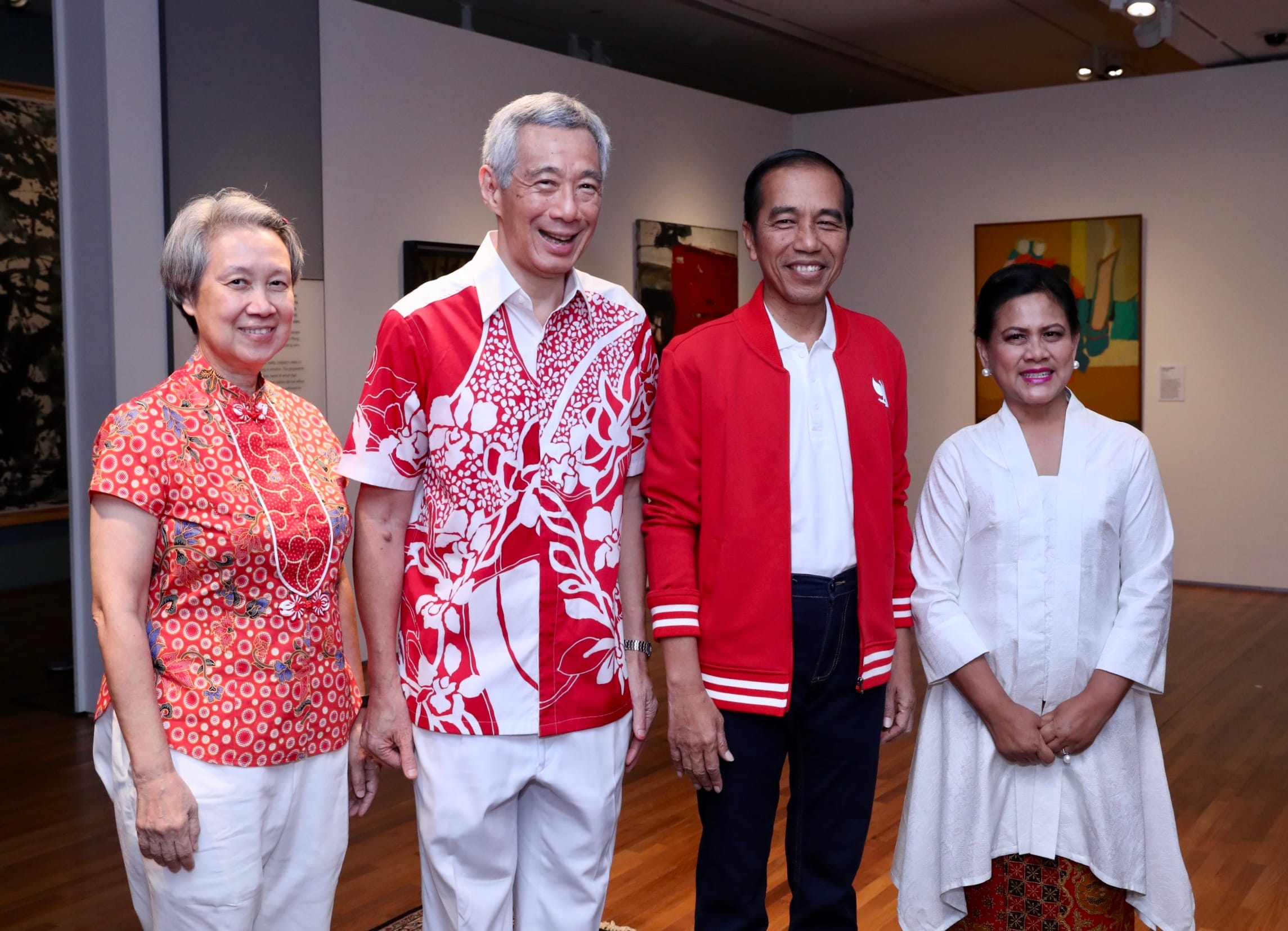 Group of four people in front of art in a gallery setting.