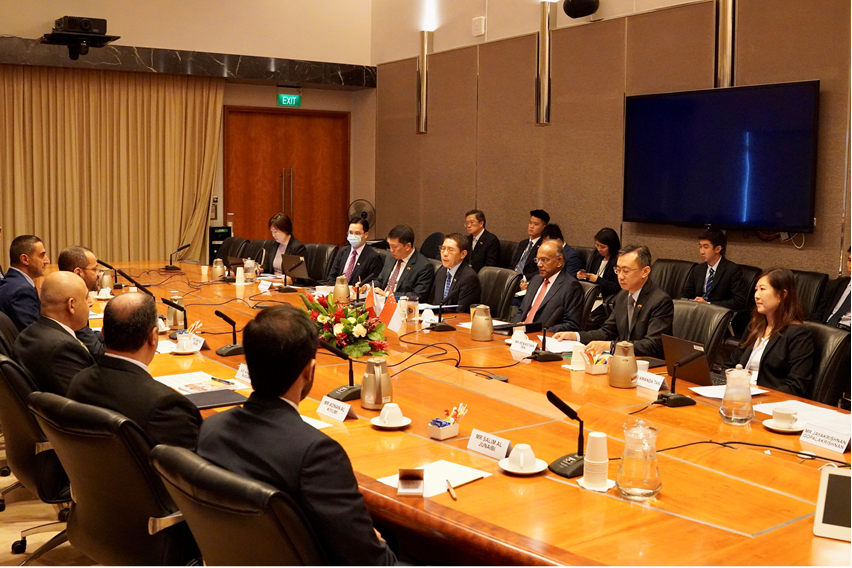 People in suits at a long conference table with microphones and place cards.