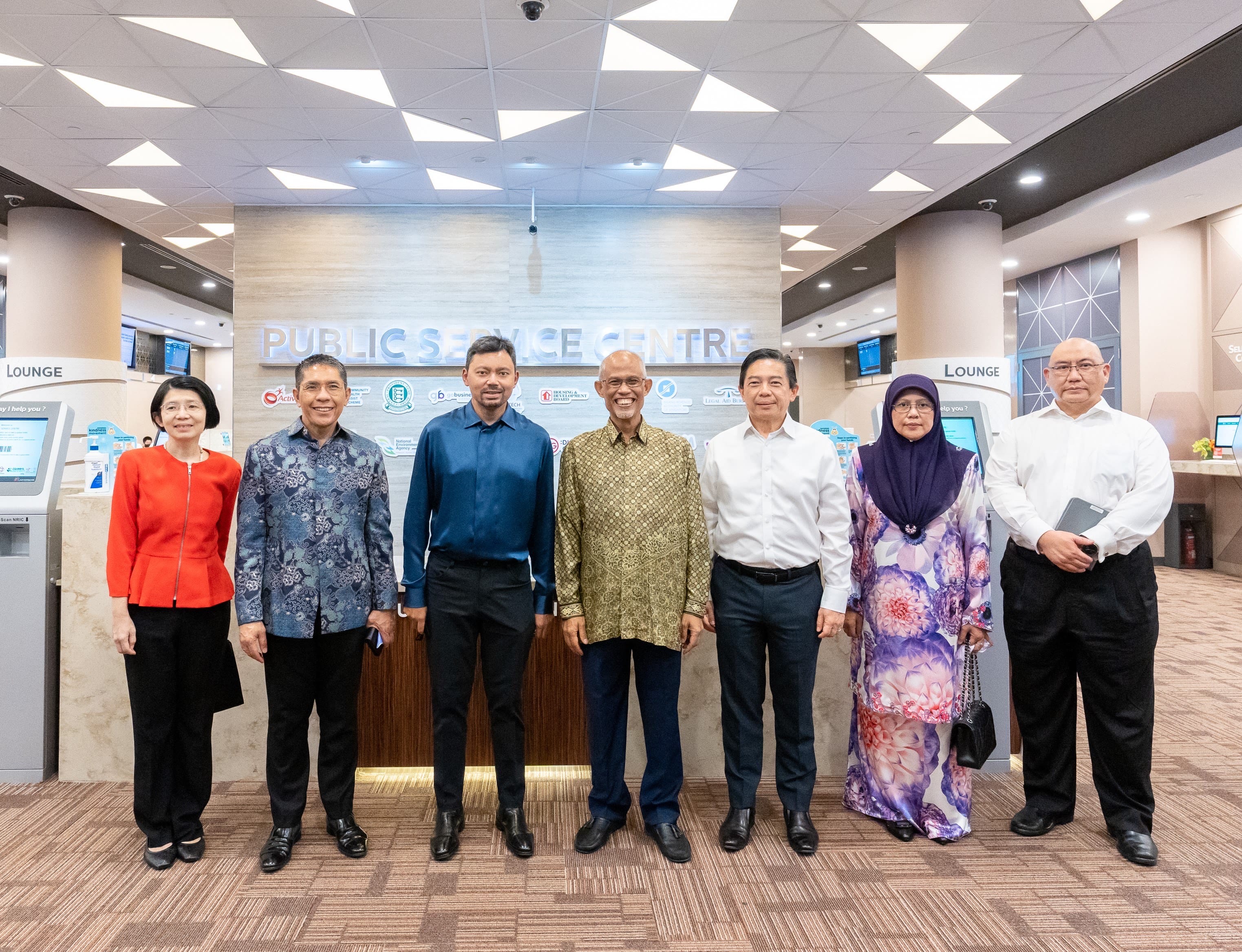 Group of seven people stand in front of "Public Service Centre" sign.