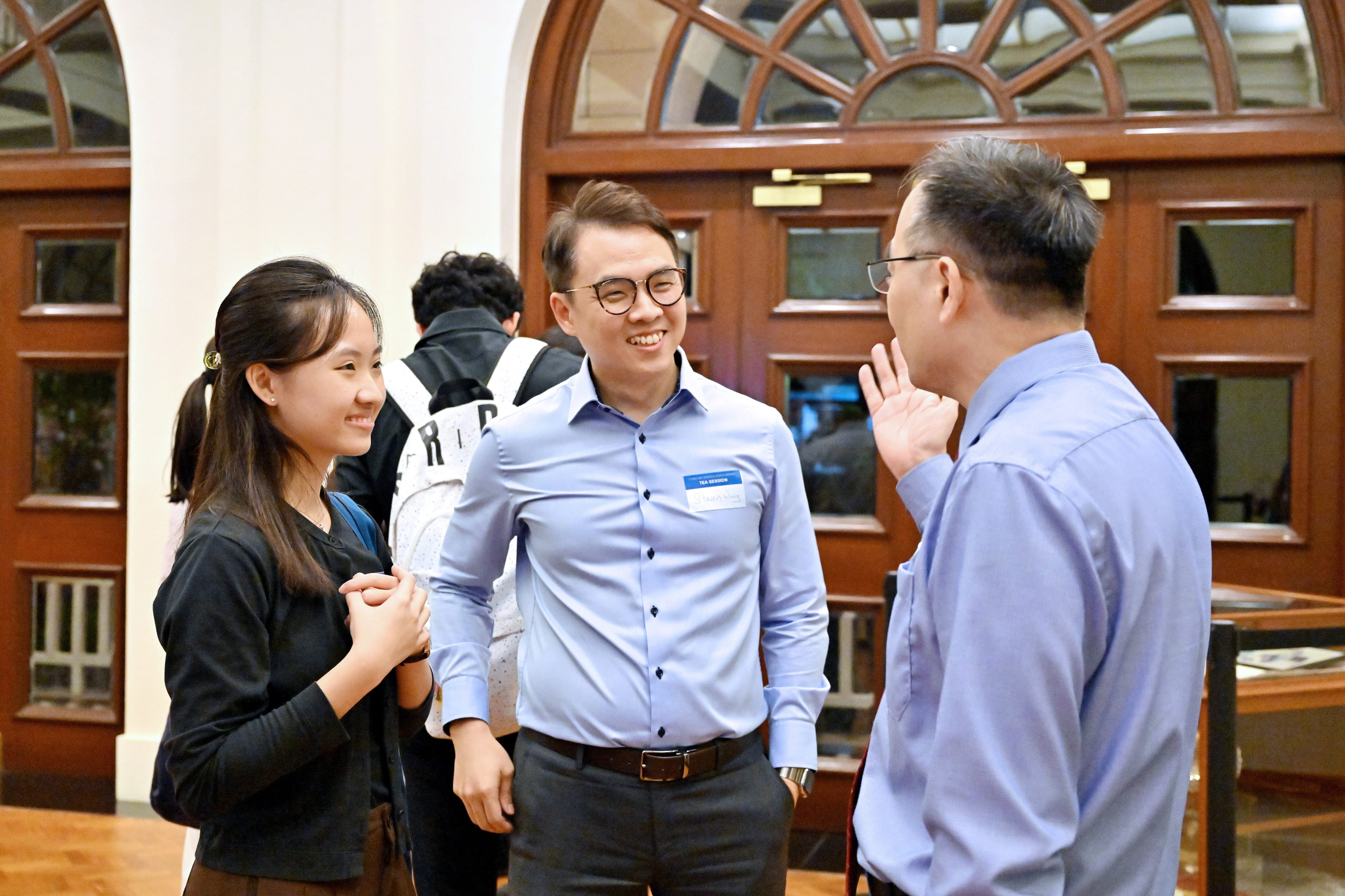 Two men and a woman in conversation during networking at the scholarship event