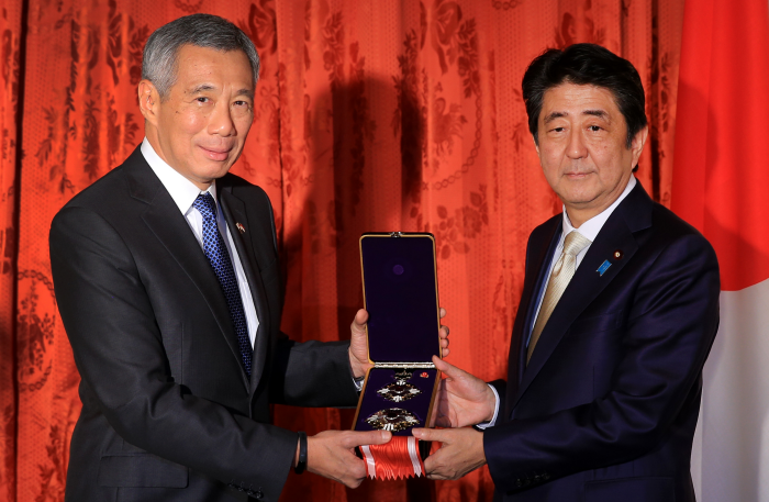 Lee Hsien Loong presents Shinzo Abe with an award in a velvet lined case.