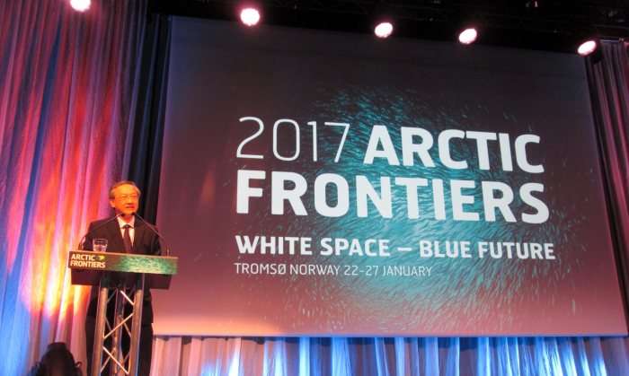 Man at "Arctic Frontiers" podium, with event banner backdrop.