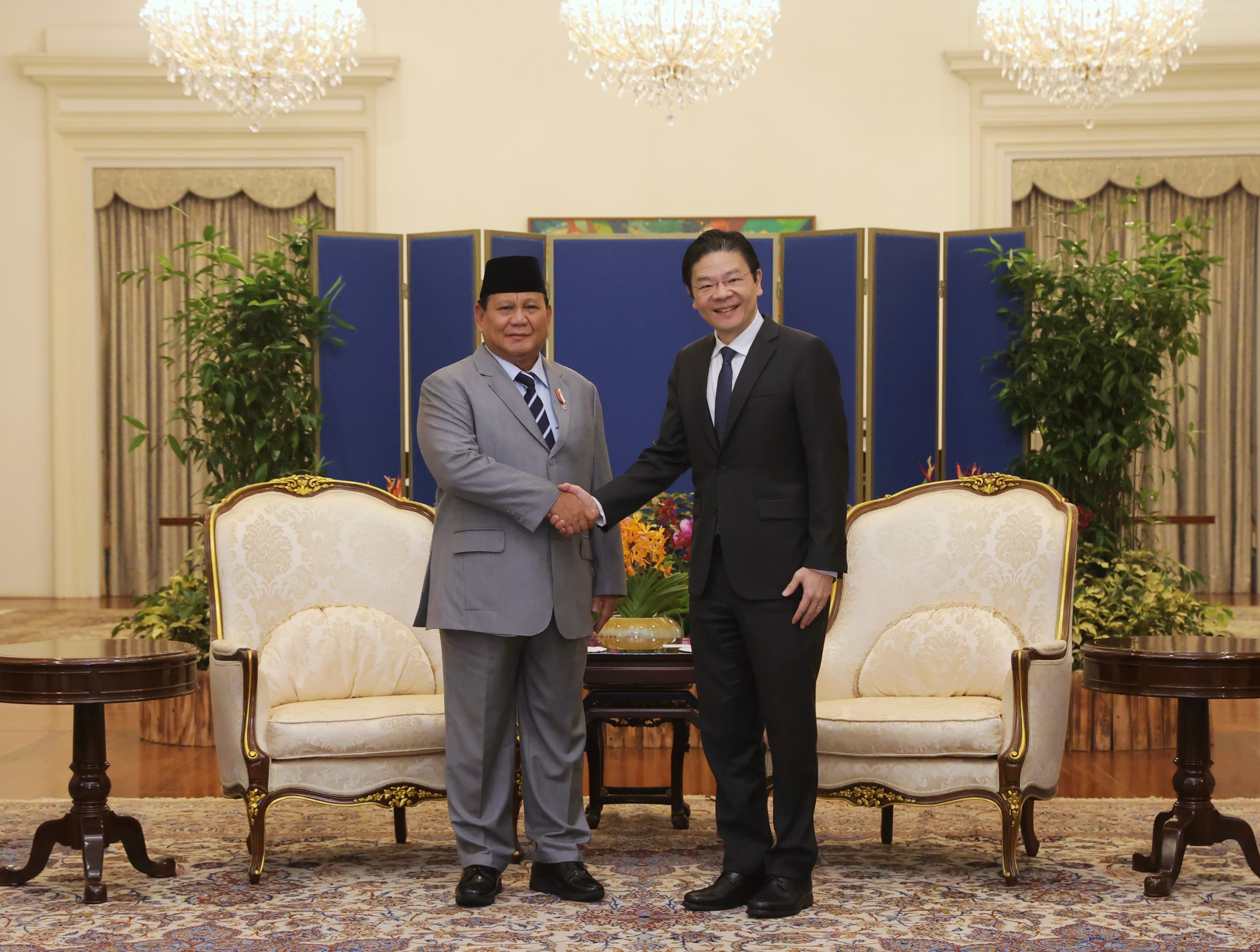 Justin Trudeau and Lee Hsien Loong sit facing each other in armchairs in a decorated room.