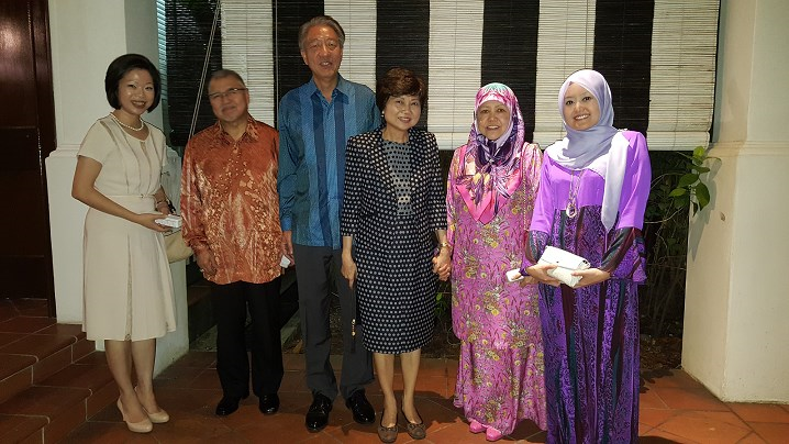 Group of six people in formal wear, two in hijabs, posing indoors.