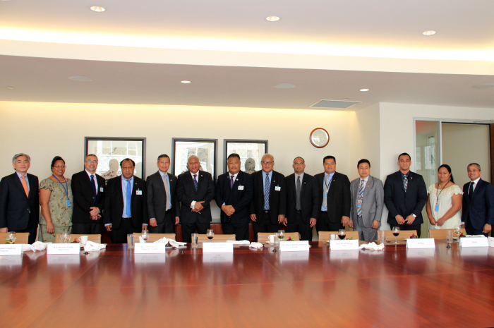 A group of people standing behind a long conference table.