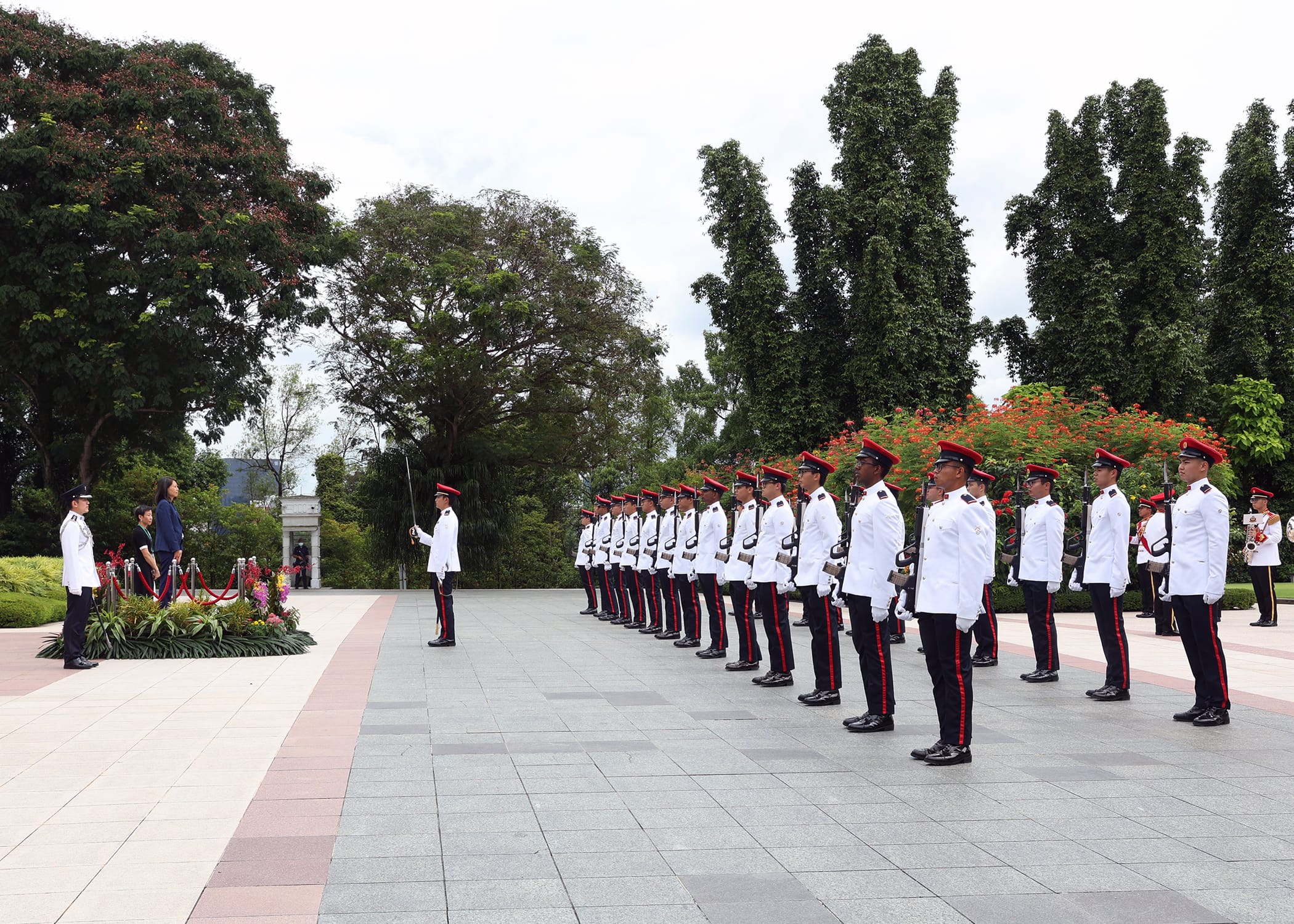 Military honor guard standing in formation; officials on a podium in the background.
