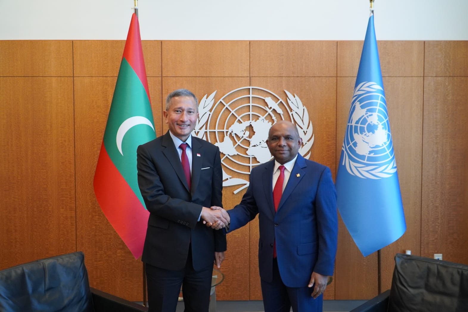Two men in suits shaking hands; flags of Maldives and the UN in background.